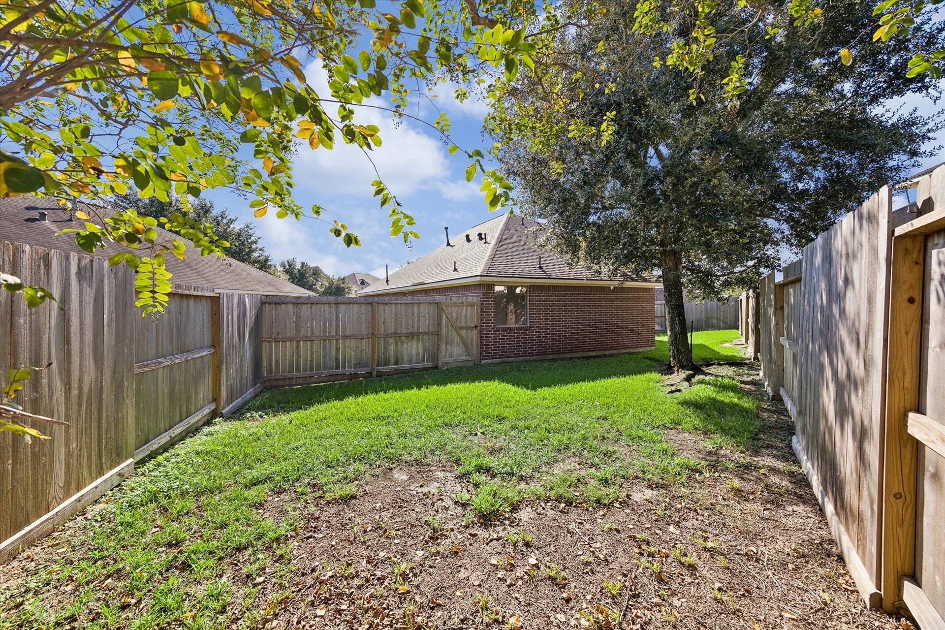 18127 Hillock Glen Lane, Cypress, TX 77429 Additional view of the fenced backyard featuring mature trees, open green space, and covered patio.
