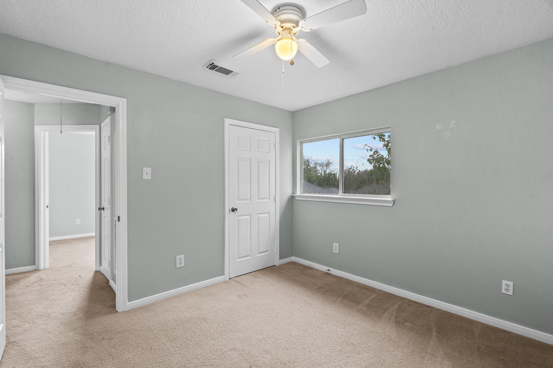 5800 Winding Brook Drive, Dickinson, TX 77539 Bright and cozy bedroom with soft gray walls, plush carpeting, and a ceiling fan.