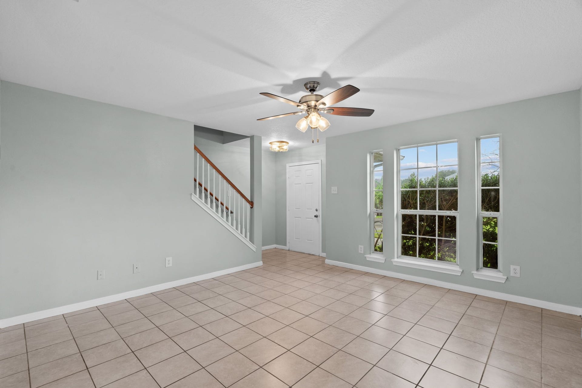 5800 Winding Brook Drive, Dickinson, TX 77539 Bright living area with large windows, neutral tile flooring, and a ceiling fan.