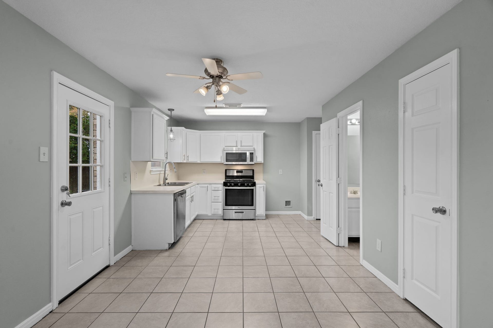 5800 Winding Brook Drive, Dickinson, TX 77539 Bright and spacious kitchen with modern stainless steel appliances, ample white cabinetry, and a convenient tile floor.