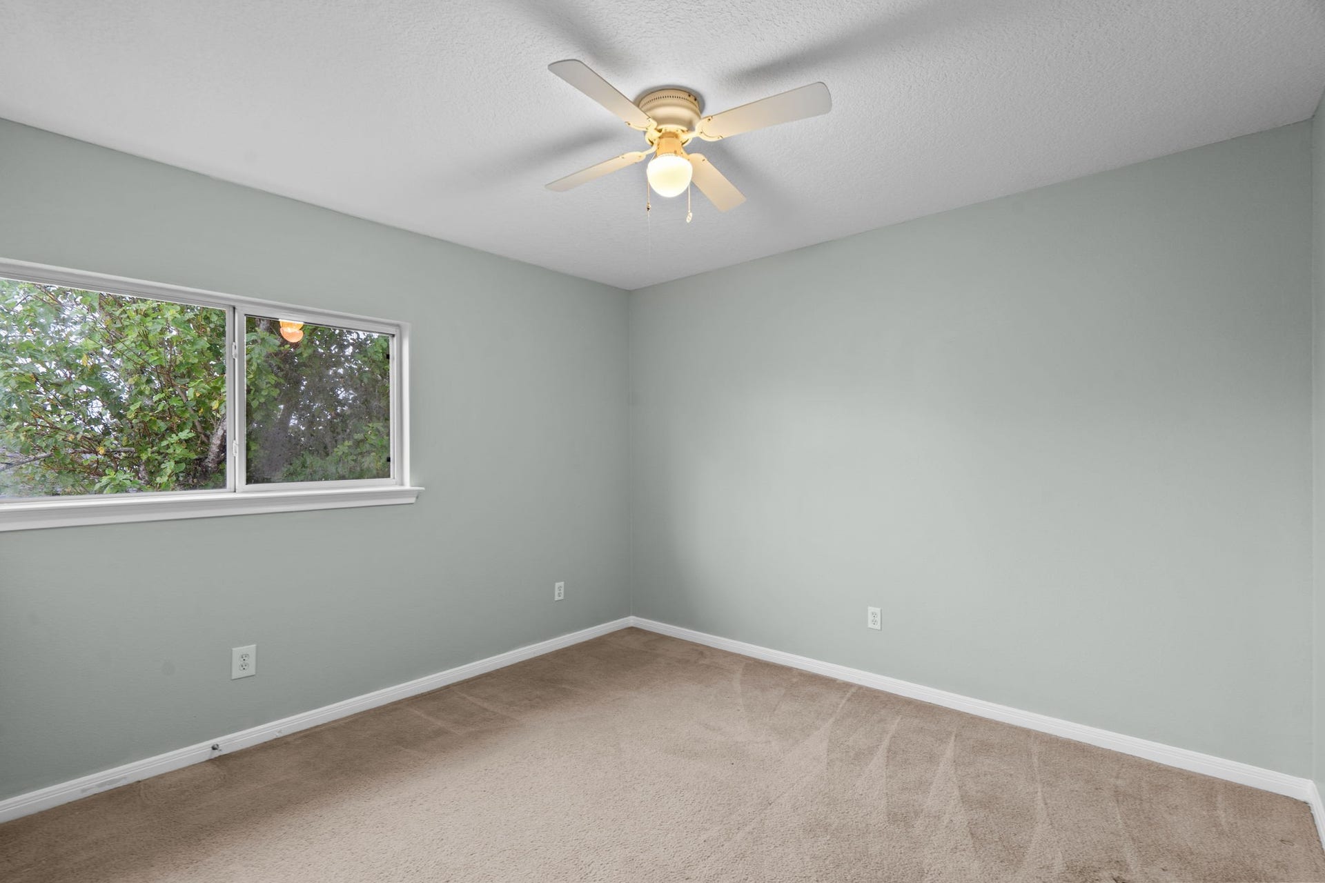 5800 Winding Brook Drive, Dickinson, TX 77539 Bright and cozy bedroom with soft gray walls, plush carpeting, and a ceiling fan.