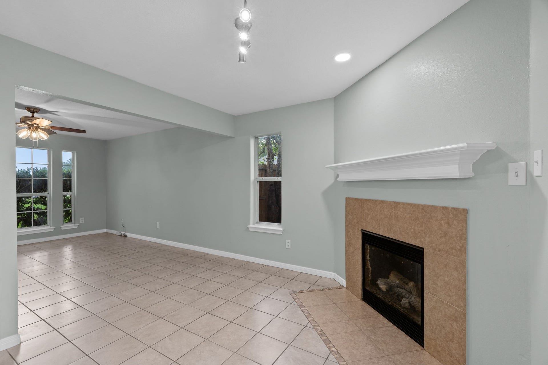 5800 Winding Brook Drive, Dickinson, TX 77539 Spacious living area features elegant tile flooring, a cozy fireplace, and abundant natural light from large windows.