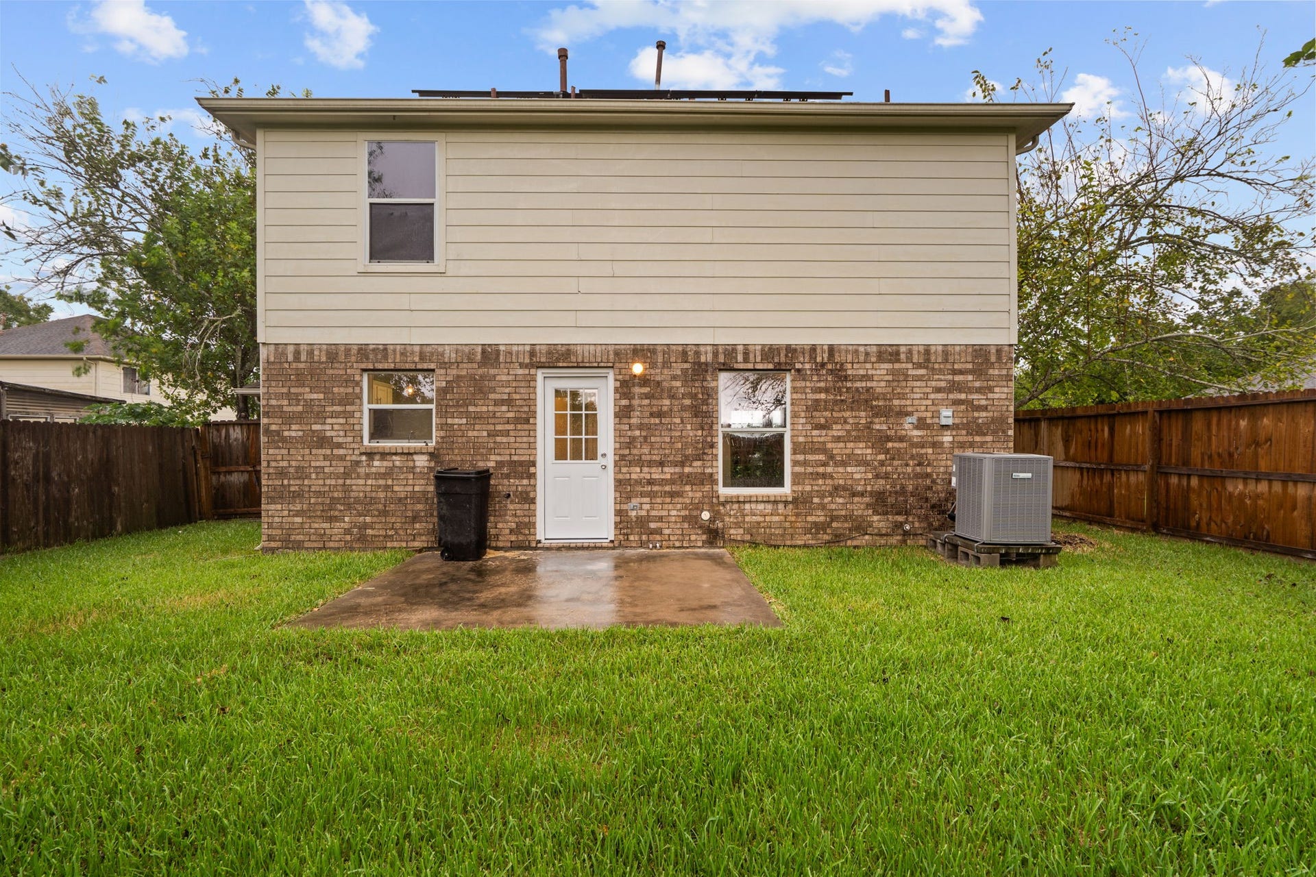 5800 Winding Brook Drive, Dickinson, TX 77539 Charming two-story home with a mix of brick and siding exterior, featuring a spacious fenced backyard and a cozy patio area perfect for outdoor gatherings.