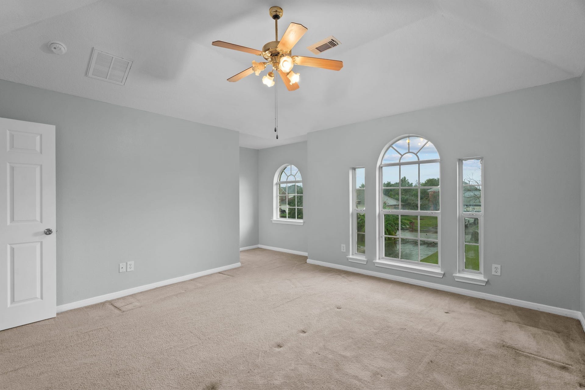 5800 Winding Brook Drive, Dickinson, TX 77539 Bright and spacious bedroom with vaulted ceilings, featuring elegant arched windows that offer scenic views and fill the room with natural light.
