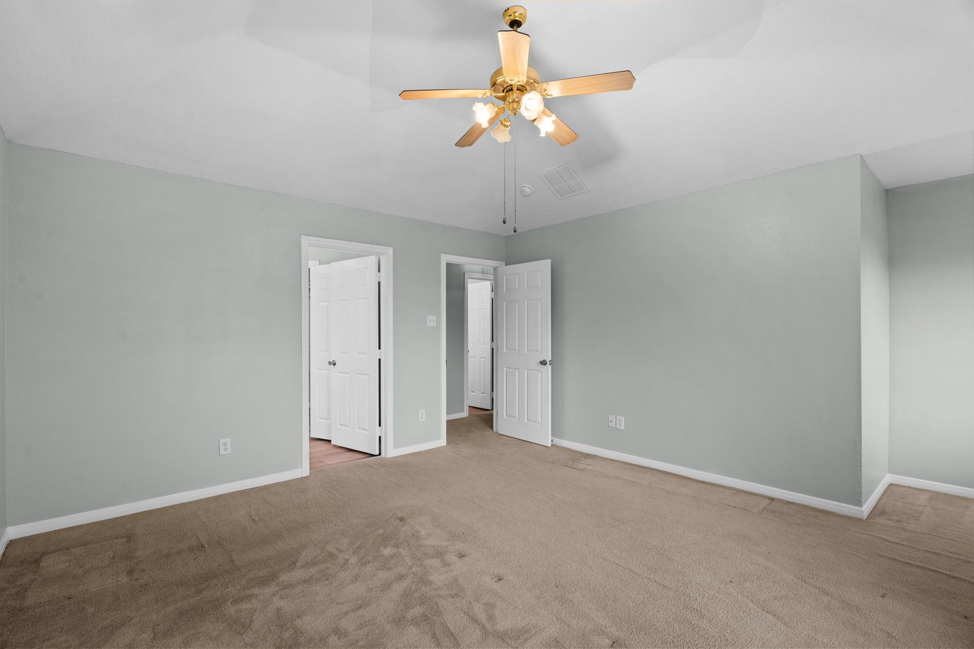 5800 Winding Brook Drive, Dickinson, TX 77539 Spacious bedroom with soft green walls, plush carpeting, and a ceiling fan.