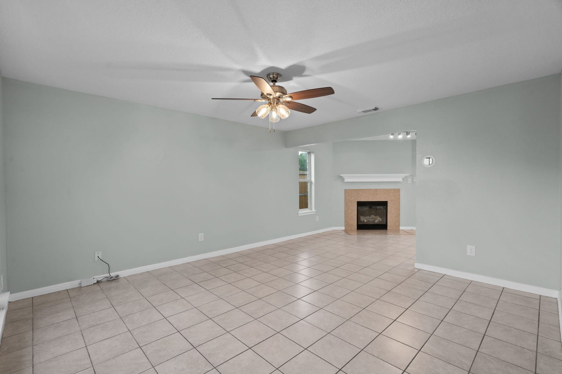 5800 Winding Brook Drive, Dickinson, TX 77539 Spacious living area featuring a ceiling fan, fireplace, and large tile flooring, offering a cozy and inviting atmosphere.