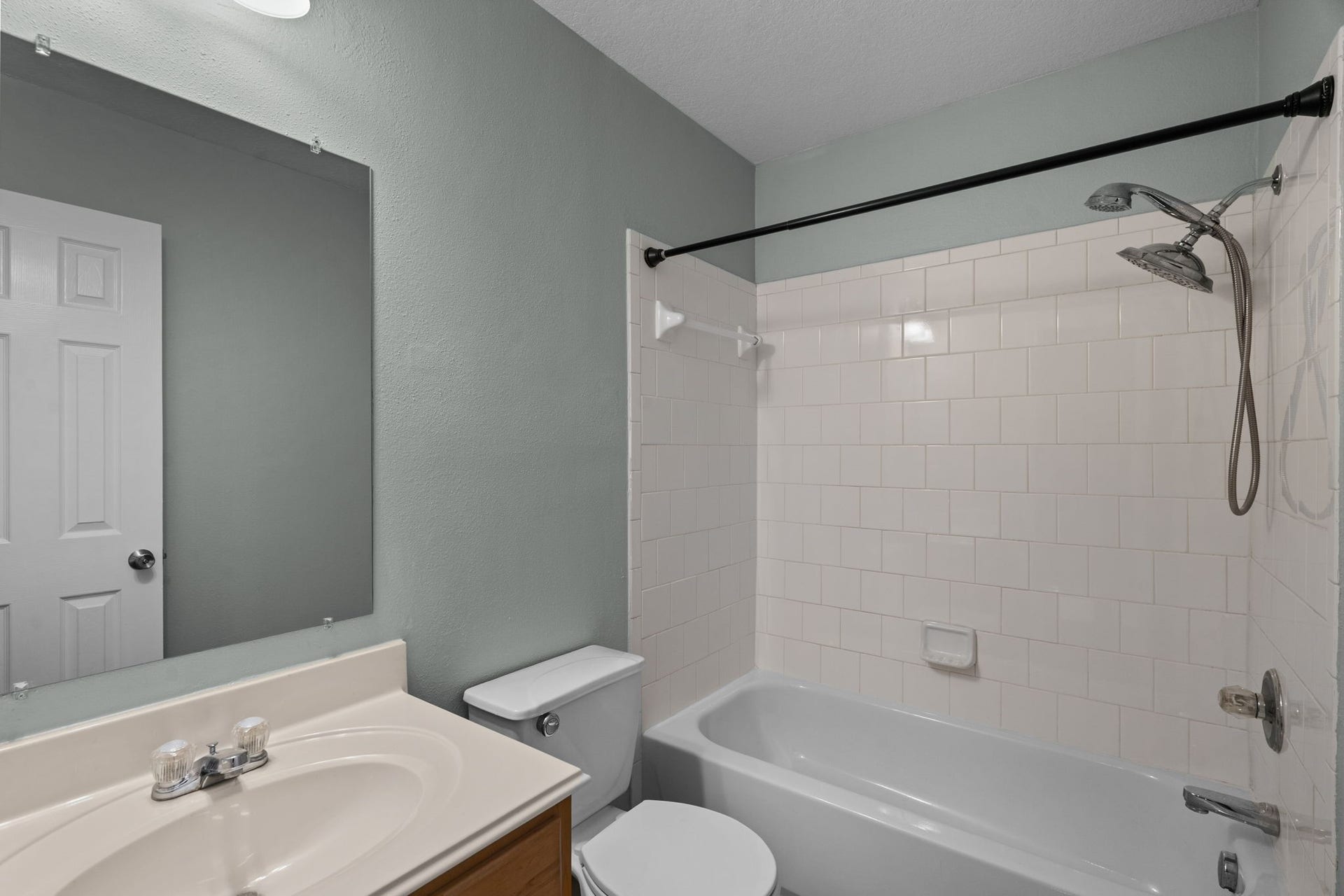 5800 Winding Brook Drive, Dickinson, TX 77539 Bright and clean bathroom featuring a classic white tiled shower-tub combo, sleek vanity with ample lighting, and modern fixtures.