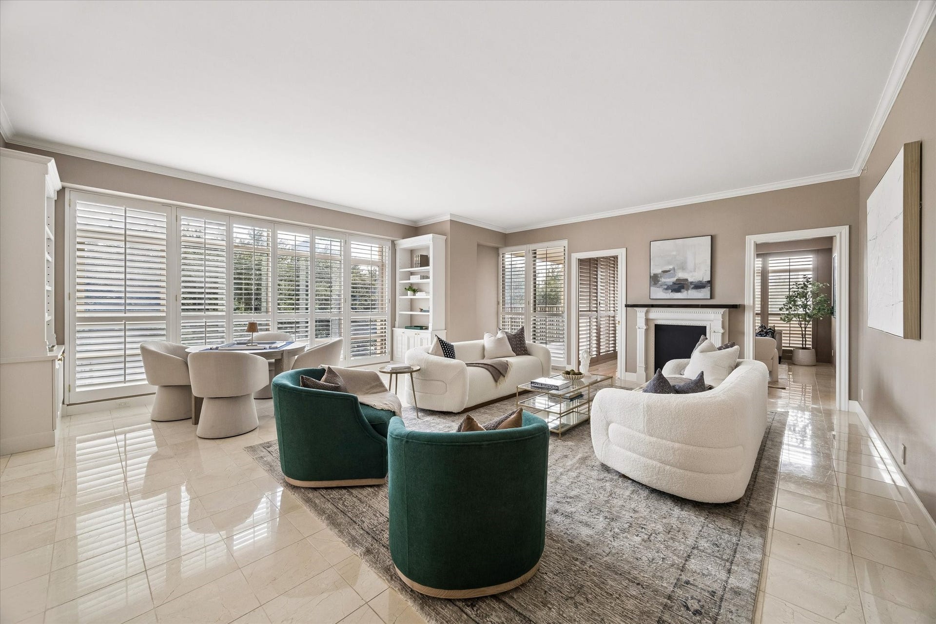 Living room with wall of windows looking east. Plantation shutters on all windows.  Two doorways flanking mock fireplace open to study.