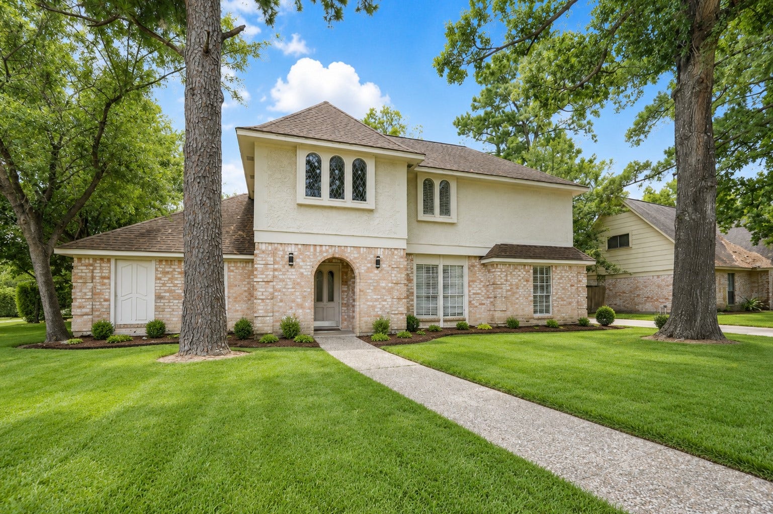 11711 Gardenglen Drive, Houston, TX 77070 Charming two-story home with a classic brick facade, nestled among mature trees, featuring a welcoming arched entryway, and a winding front path. Offering inviting curb appeal.