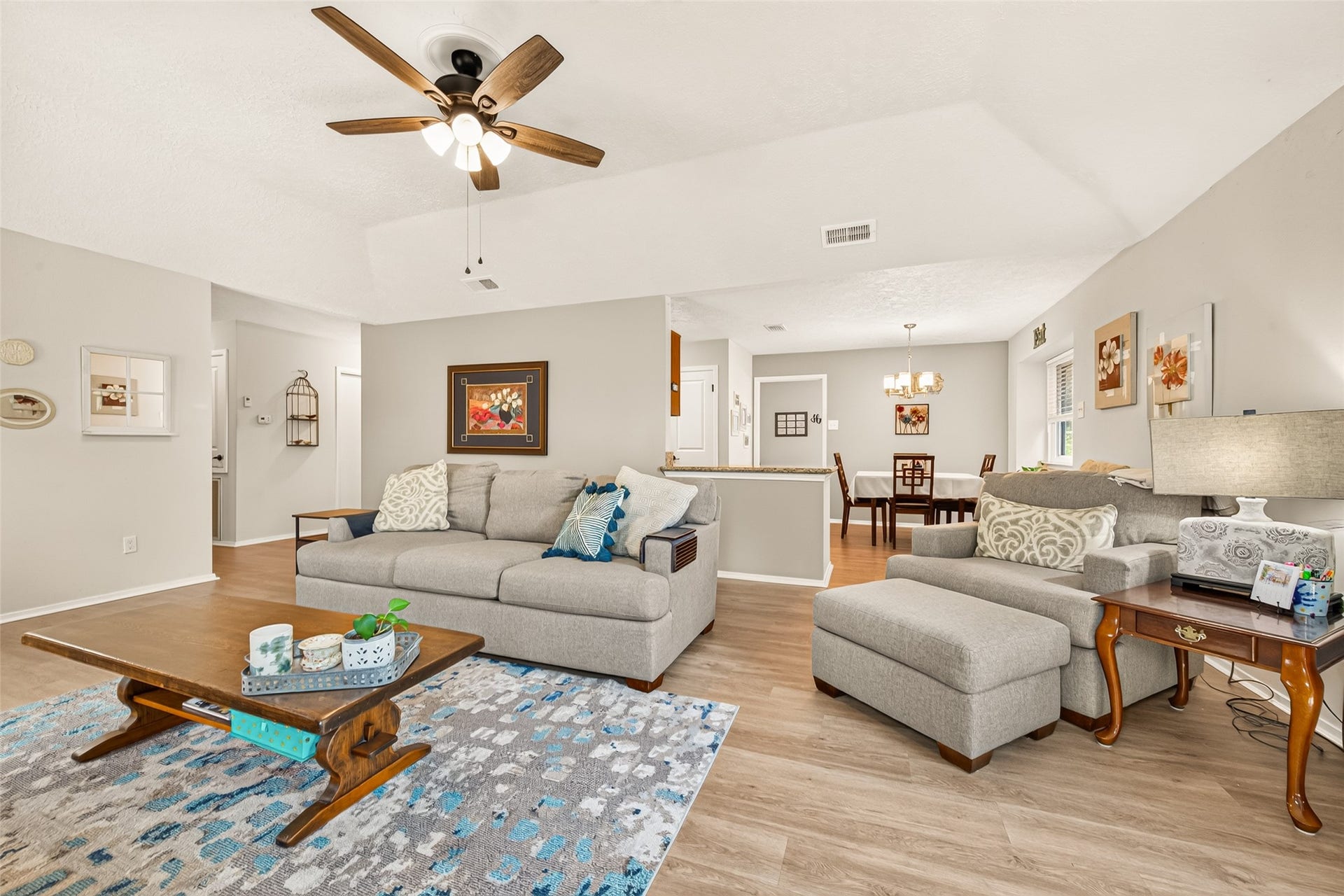 2123 Collingsfield Drive, Sugar Land, TX 77478 Spacious and inviting living area with modern gray tones, a ceiling fan, and an open layout leading to a dining space, perfect for entertaining.