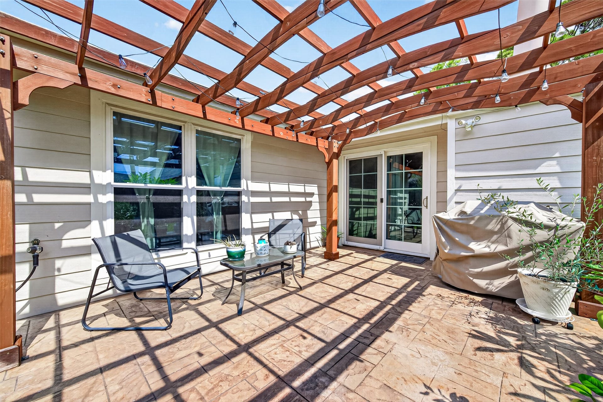 2123 Collingsfield Drive, Sugar Land, TX 77478 Charming patio with a wooden pergola, perfect for outdoor relaxation, string lights, creating an inviting atmosphere.