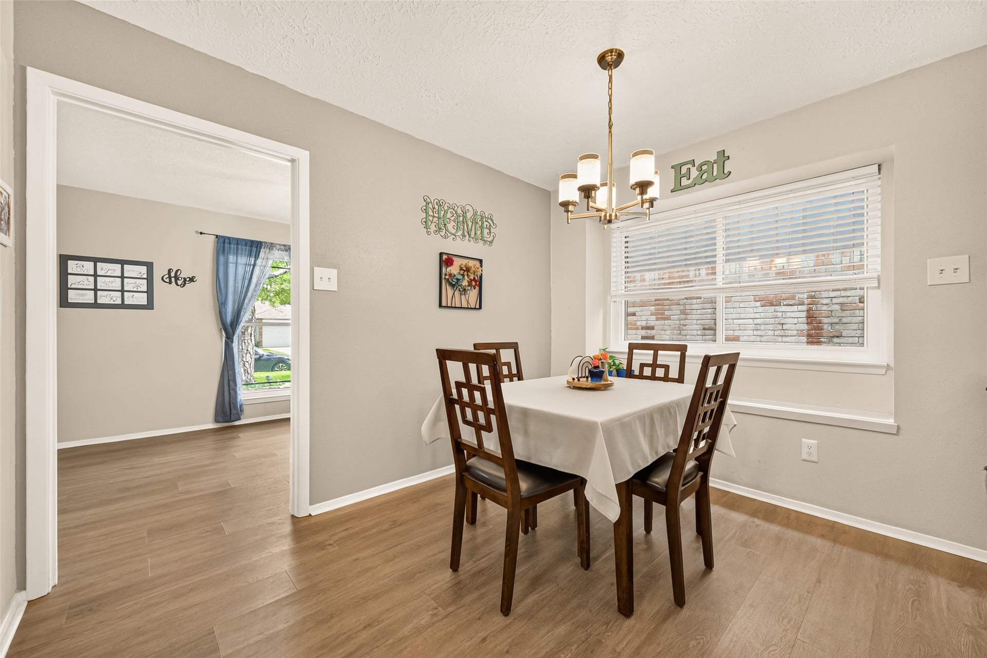 2123 Collingsfield Drive, Sugar Land, TX 77478 Cozy dining area with a modern chandelier, large window for natural light, and an inviting view into a spacious living room.