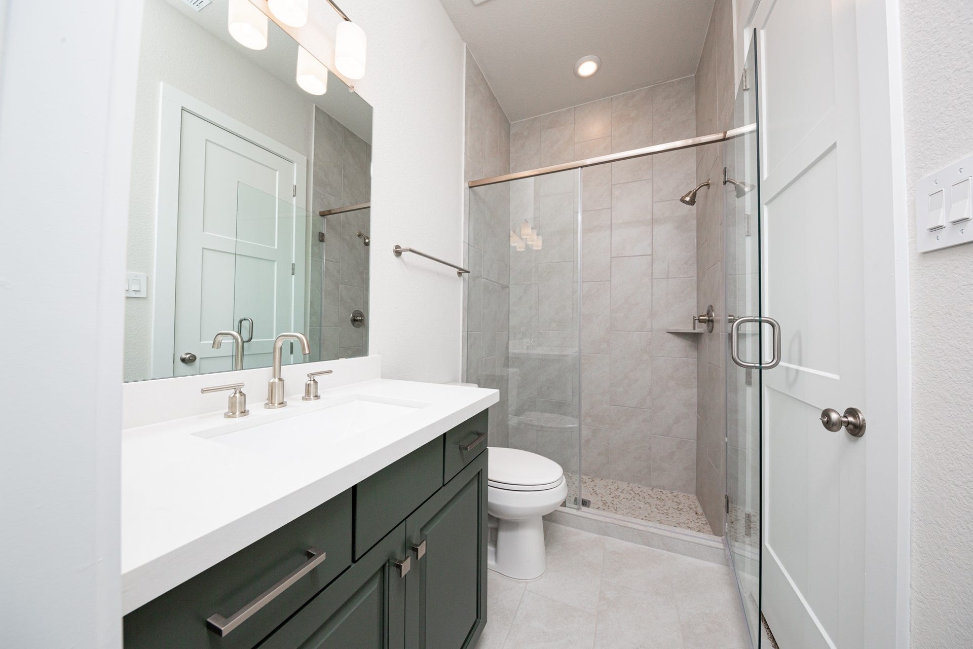 1915 Langford Street, Montgomery, TX 77316 This en-suite bathroom offers stained cabinet topped with quartz countertop and undermount sink, brushed nickel fixtures, and a large walk-in shower with tile surround.