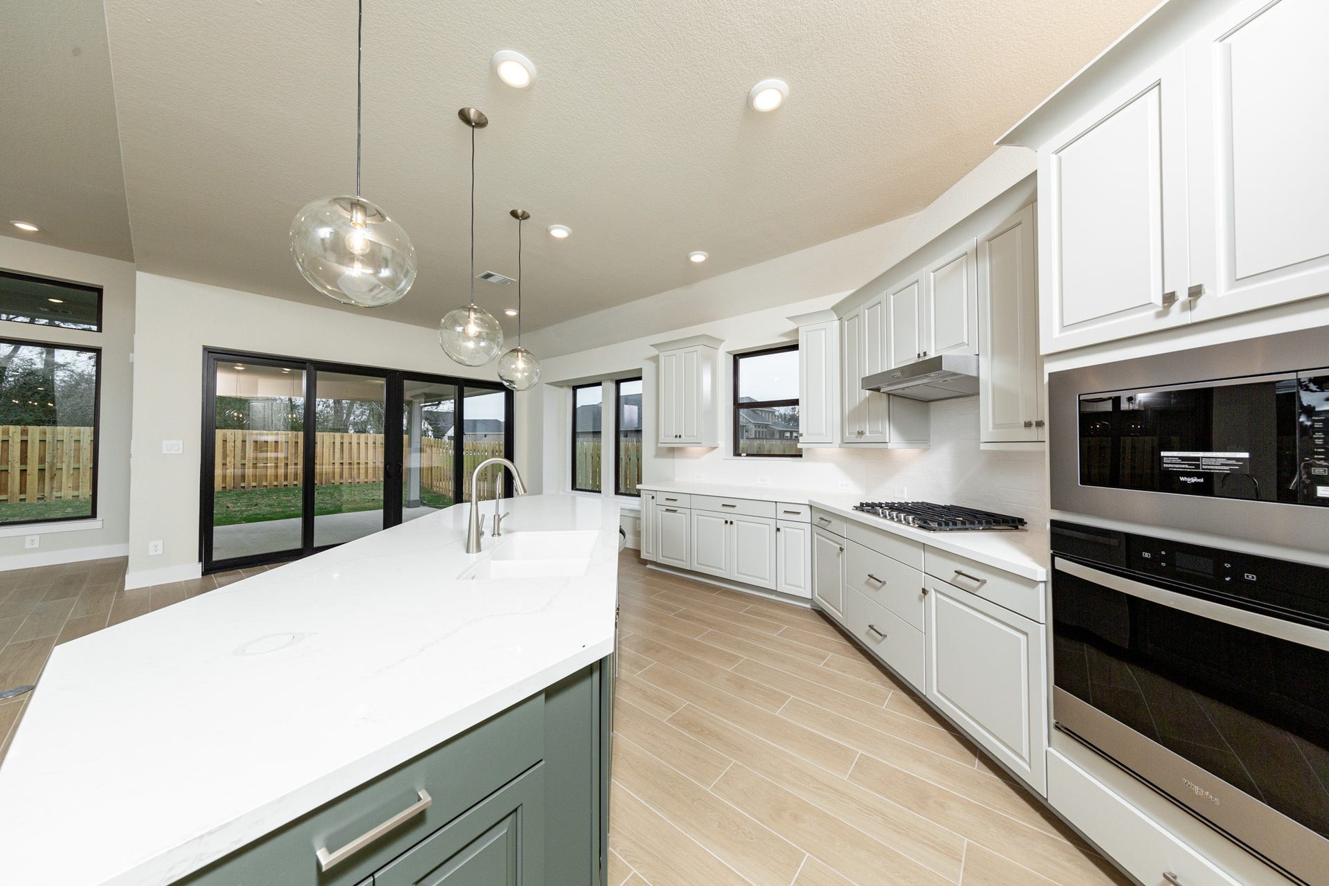 1915 Langford Street, Montgomery, TX 77316 The kitchen includes Whirlpool stainless steel appliances: 30" gas cooktop, coordinating built-in stainless steel microwave, oven wall unit, and dishwasher suggesting a professional and polished space.
