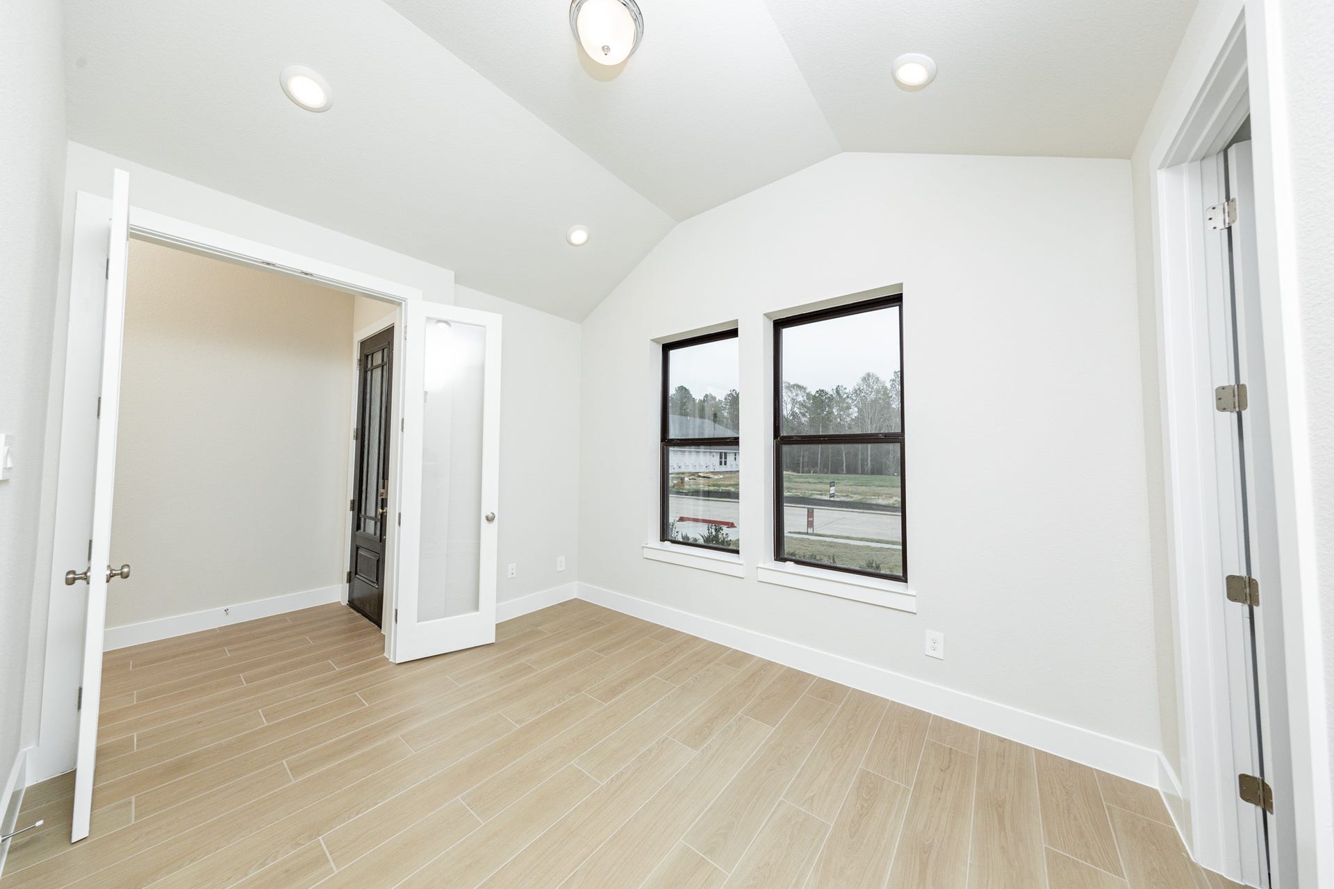 1915 Langford Street, Montgomery, TX 77316 Tucked peacefully in the front of the home is this study, which features large windows, tile flooring, French doors, and neutral toned walls.