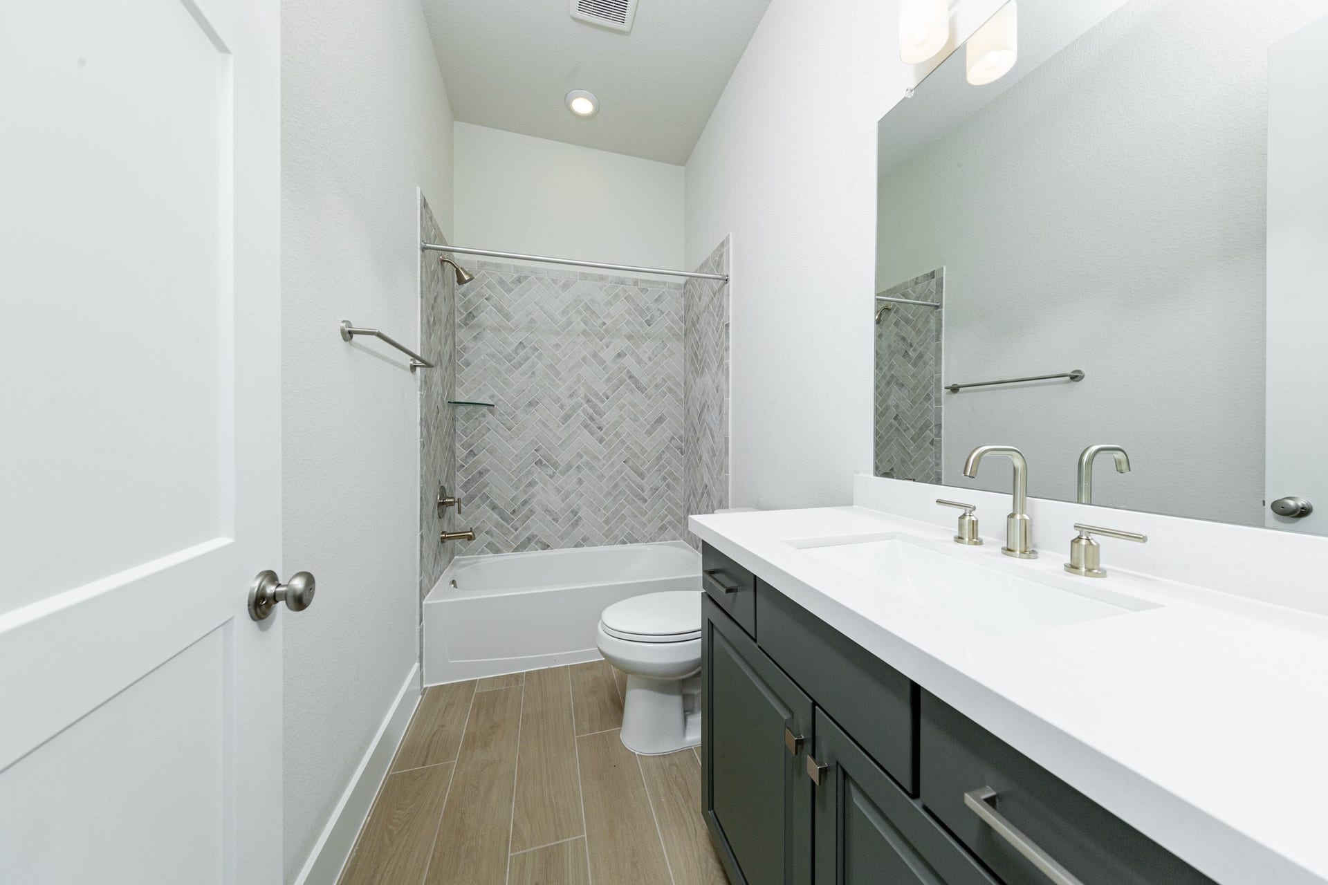 1915 Langford Street, Montgomery, TX 77316 This well-appointed secondary bathroom offers exceptional functionality with its stained cabinet topped with pristine white quartz countertops and undermount sink. Sleek, polished fixtures complement the expansive vanity mirror and chic light vanity fixture.