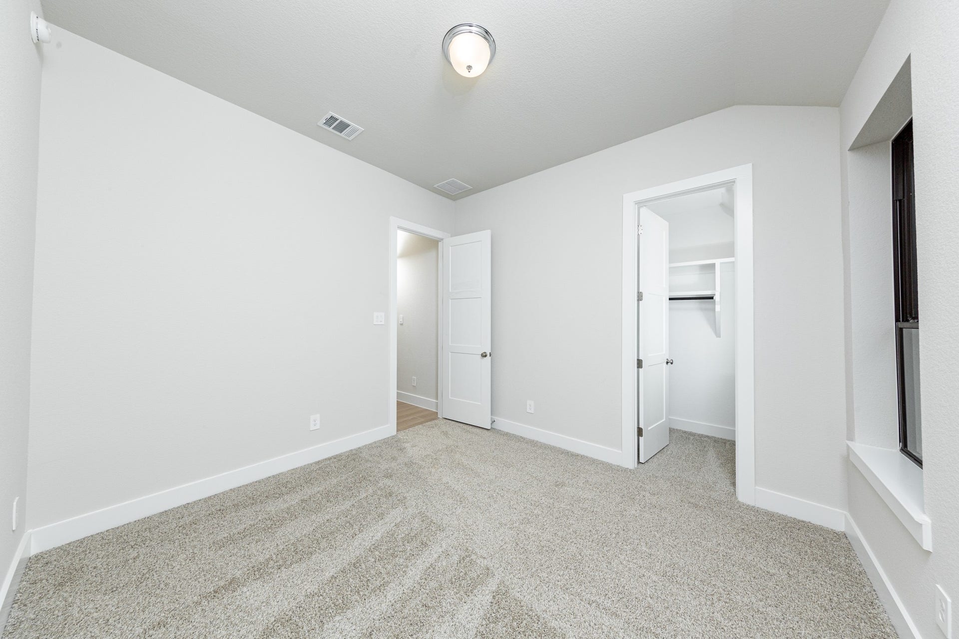 1915 Langford Street, Montgomery, TX 77316 This secondary bedroom offers comfort and style with plush carpeting, neutral paint tones, recessed lighting, large windows, and a walk-in closet.