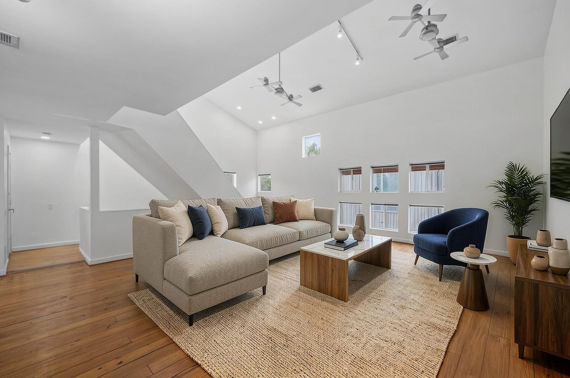 6128 Grand Boulevard, Houston, TX 77021 The second-floor living room opens with soaring ceilings, hardwood floors, oversized windows, and strong natural light. The space feels elevated, open, and connected to the dining and kitchen areas. Virtually staged.