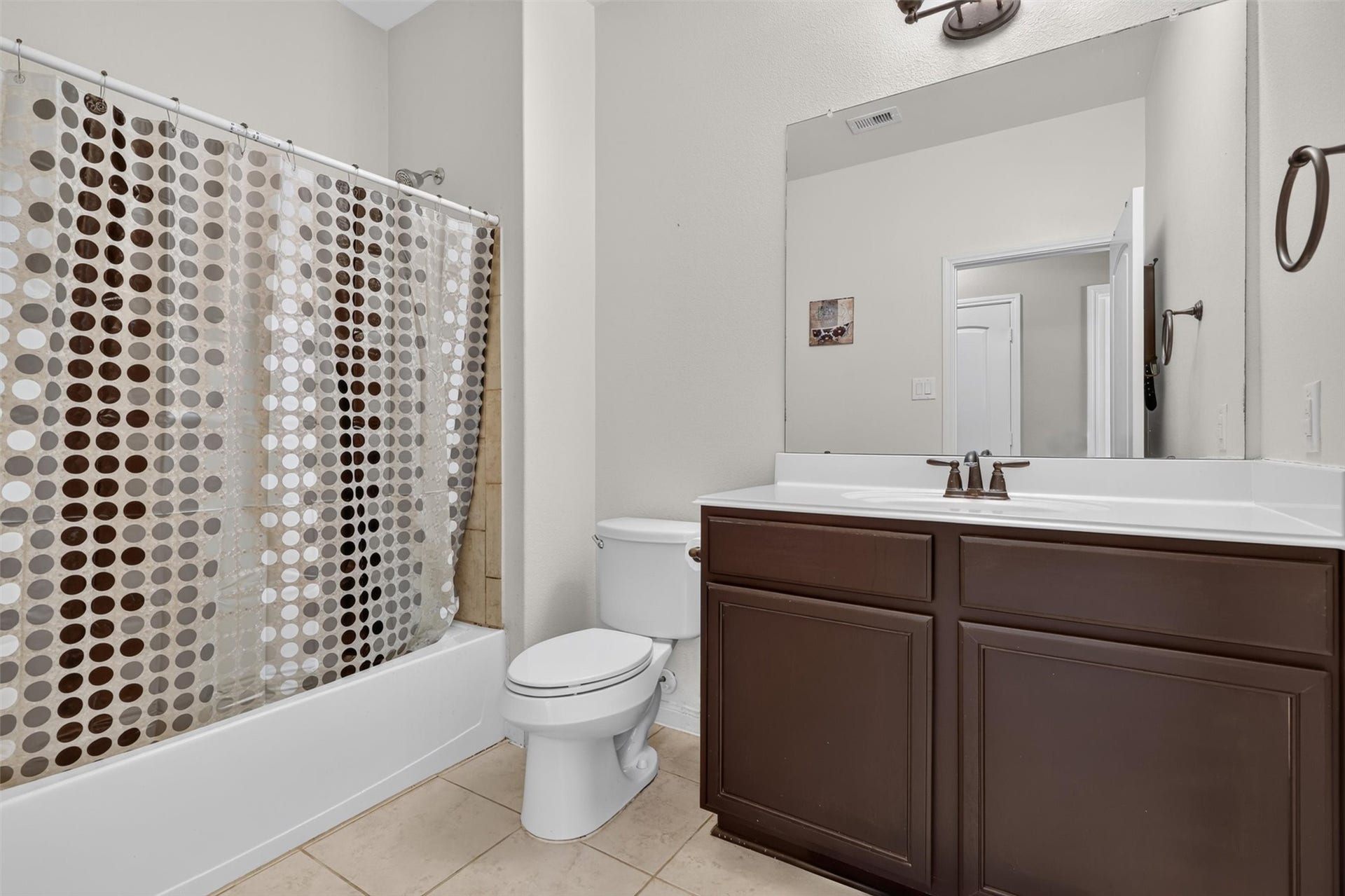 22907 Gentle Shadow Drive, Hockley, TX 77447 Everyday convenience meets classic style in the second full bathroom. A wide vanity offers generous counter space and cabinet storage, complemented by a large mirror and bronze-toned fixtures. The tub-and-shower combination provides flexibility for a quick rinse or a relaxing soak