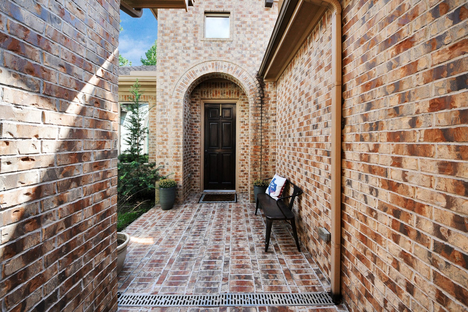 143 Pronghorn Place, Montgomery, TX 77316 Charming brick entryway with a welcoming arch and cozy bench, leading to a classic dark wood front door.