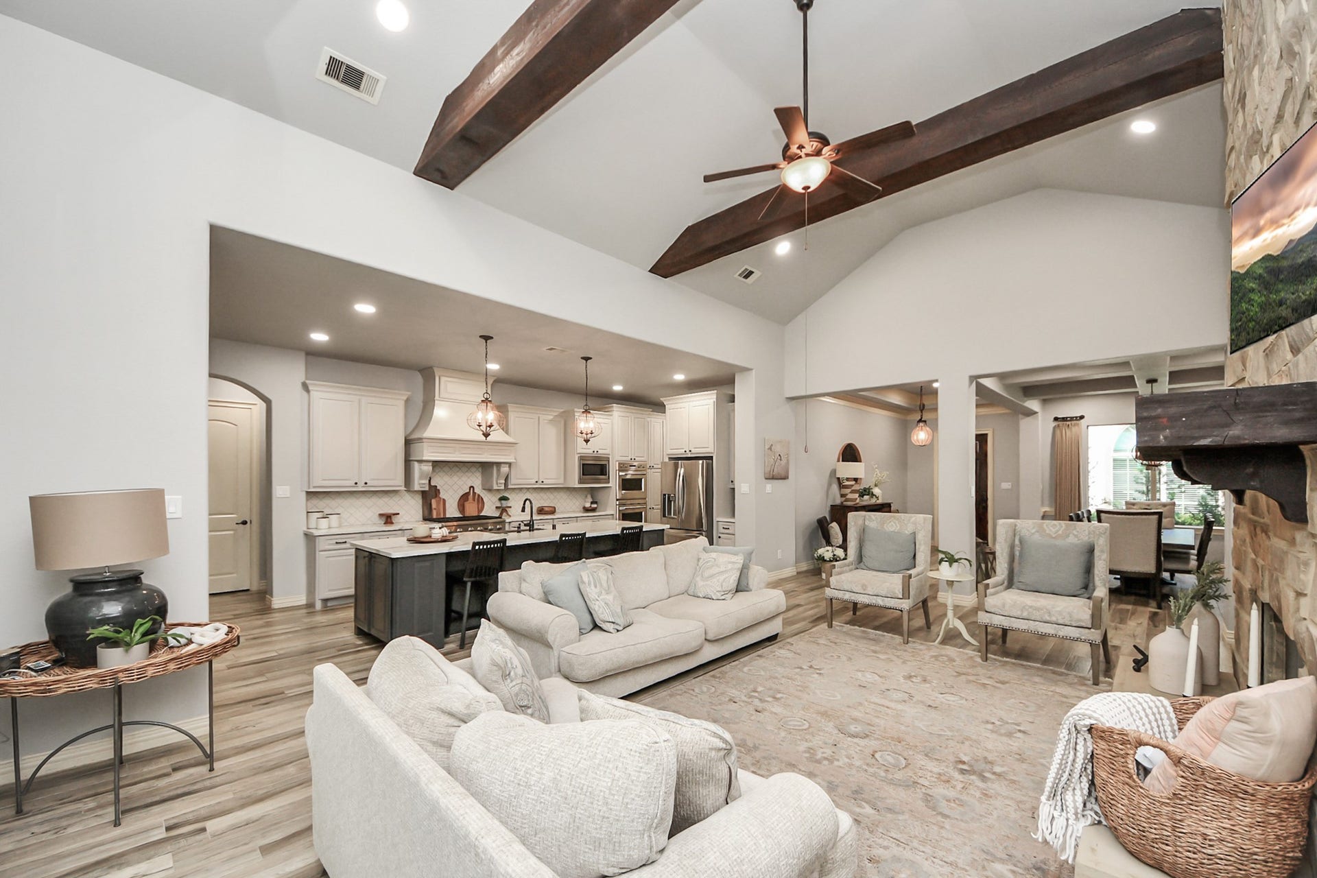 143 Pronghorn Place, Montgomery, TX 77316 Spacious open-concept living area with vaulted ceilings and exposed beams, featuring a cozy stone fireplace, elegant kitchen with modern appliances, and an inviting dining space perfect for entertaining.
