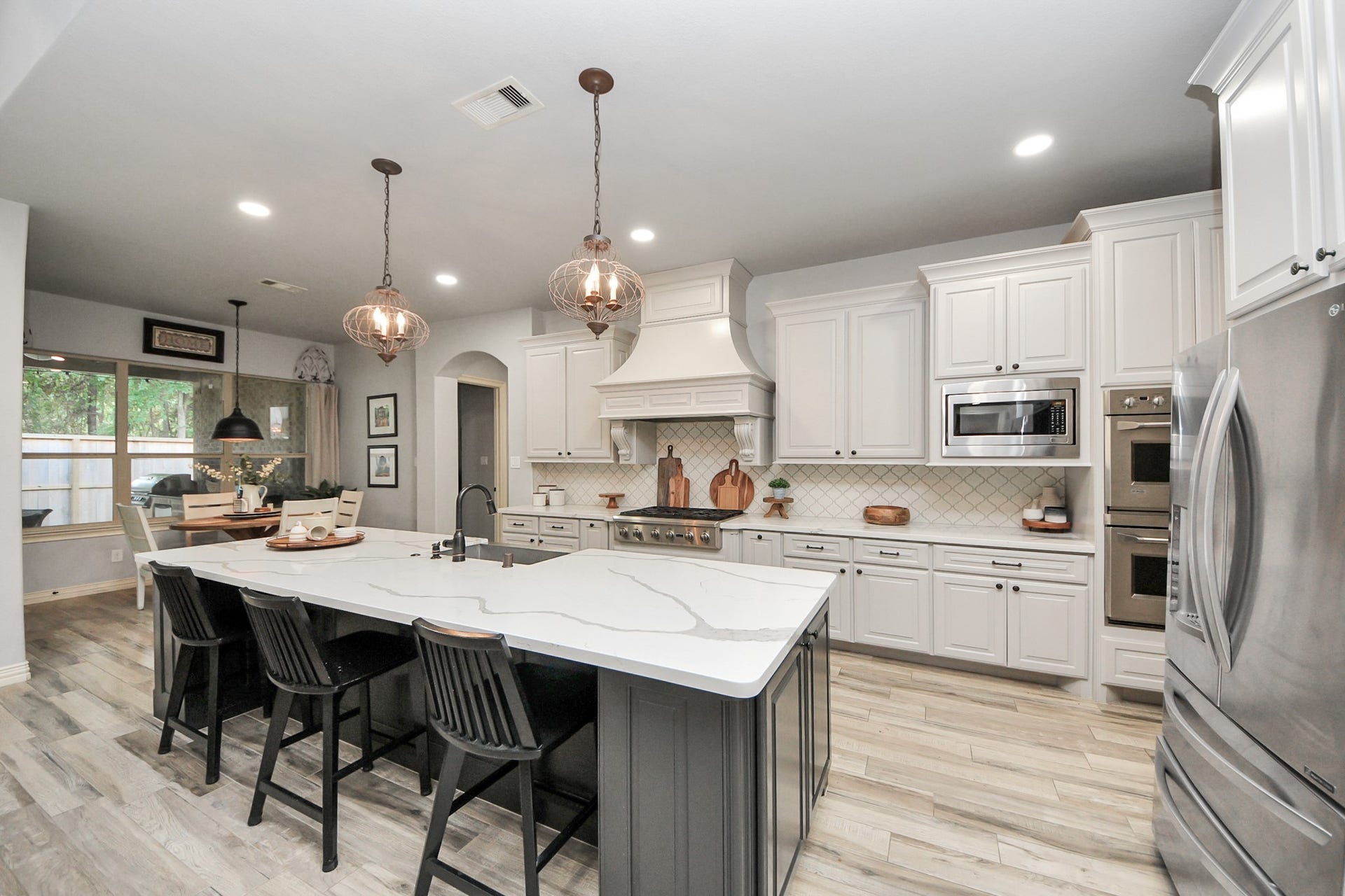 143 Pronghorn Place, Montgomery, TX 77316 Spacious kitchen featuring elegant white cabinetry, a large marble island with seating, and modern stainless steel appliances, perfect for culinary enthusiasts.