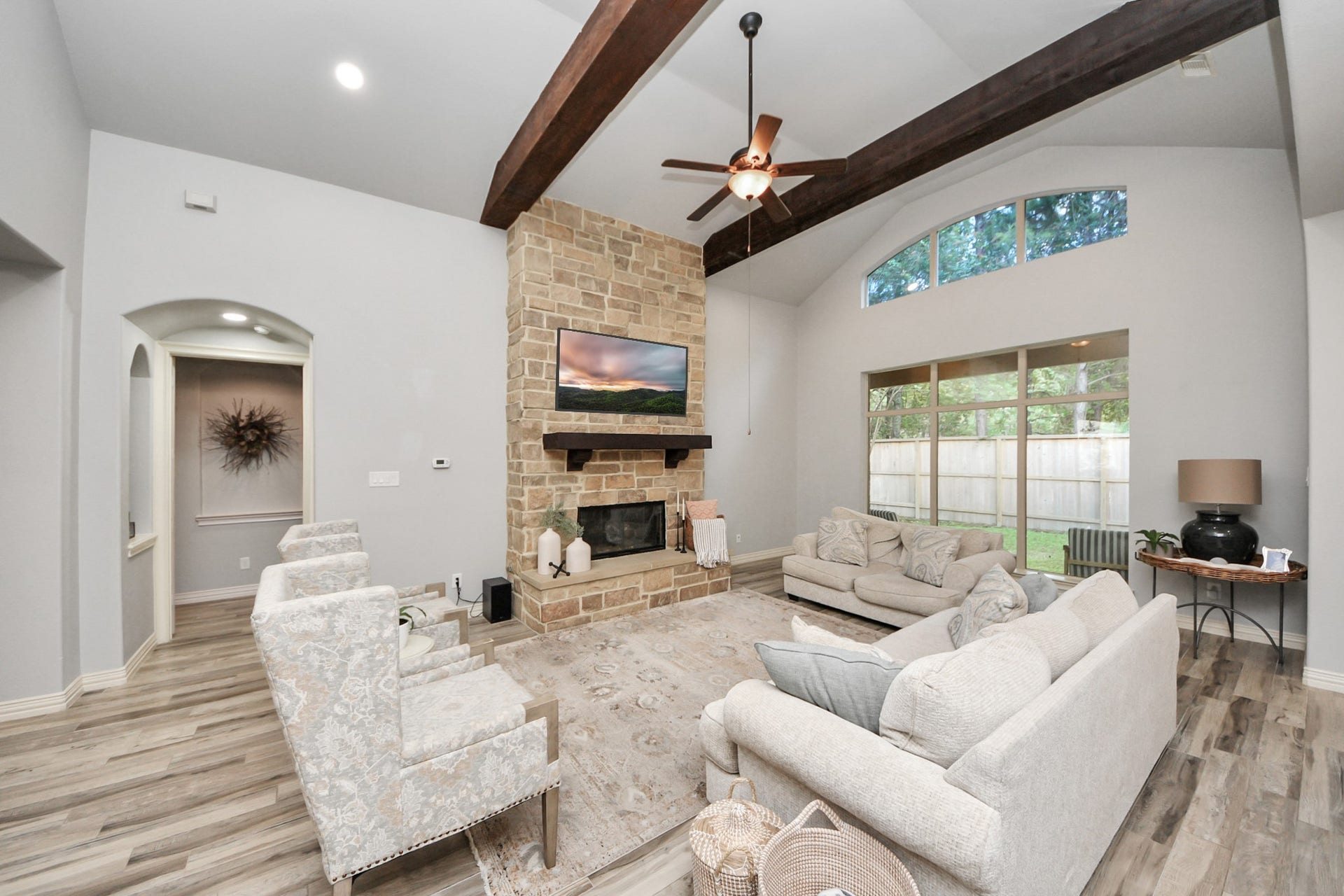 143 Pronghorn Place, Montgomery, TX 77316 Spacious living room with vaulted ceilings and exposed beams, featuring a stone fireplace and large windows offering abundant natural light.