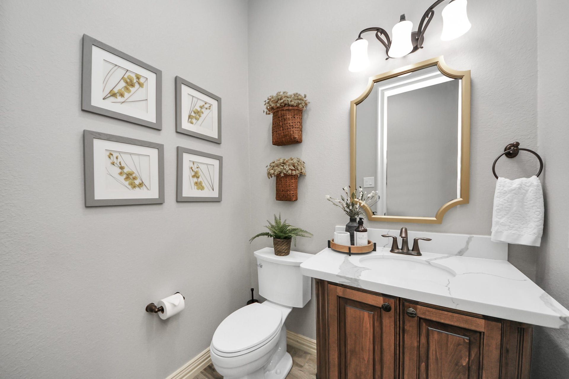 143 Pronghorn Place, Montgomery, TX 77316 Charming half-bathroom featuring a sleek marble countertop, elegant wooden cabinetry, and stylish wall decor, complemented by warm lighting and contemporary fixtures.