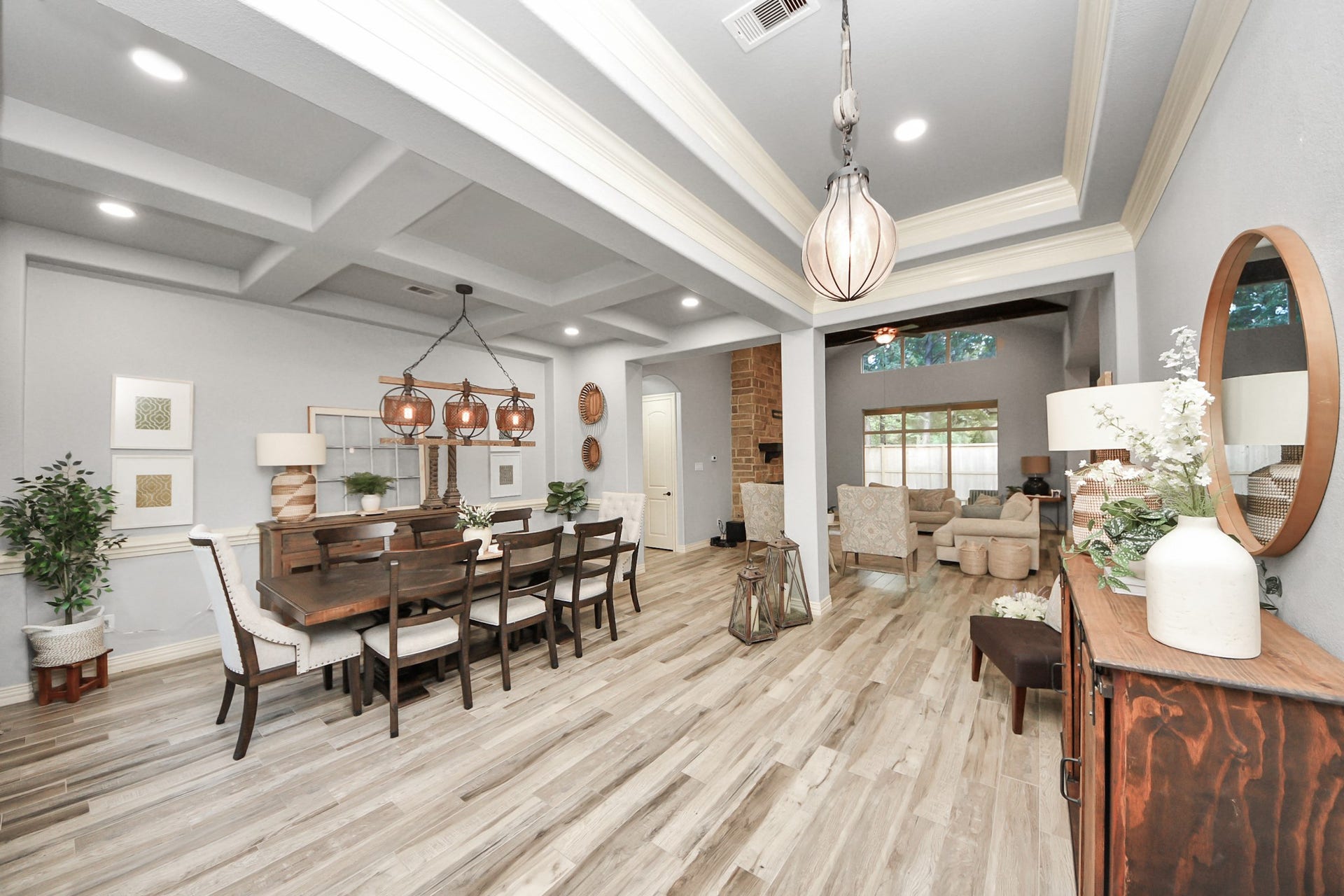 143 Pronghorn Place, Montgomery, TX 77316 Elegant dining and living area featuring coffered ceilings, stylish light fixtures, and an open layout with a cozy seating area and large windows.