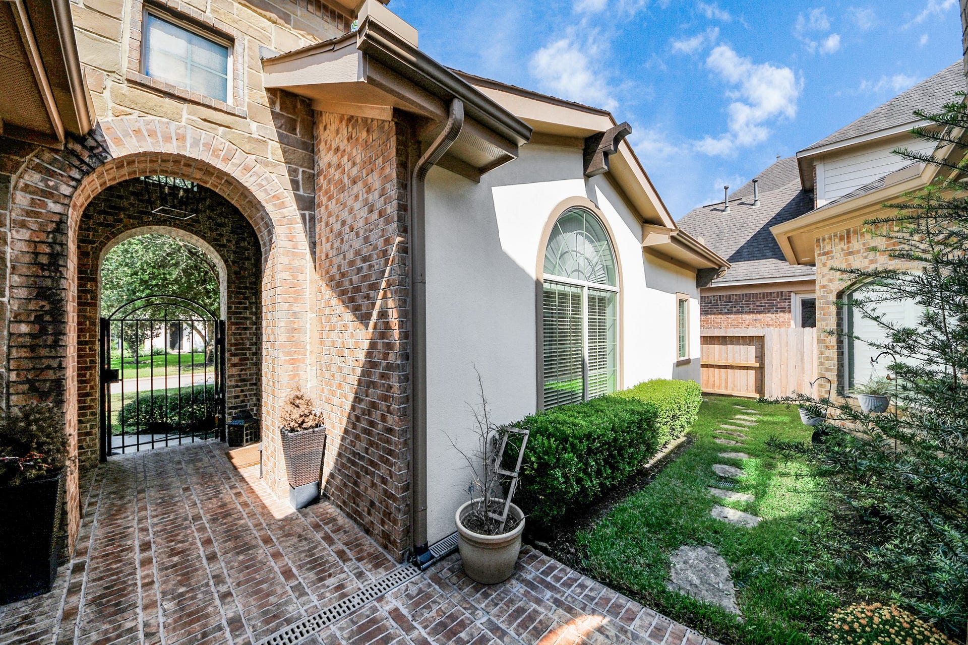 143 Pronghorn Place, Montgomery, TX 77316 Charming brick archway leads to a gated entrance, complemented by a manicured path and elegant window details, offering a welcoming and secure ambiance.