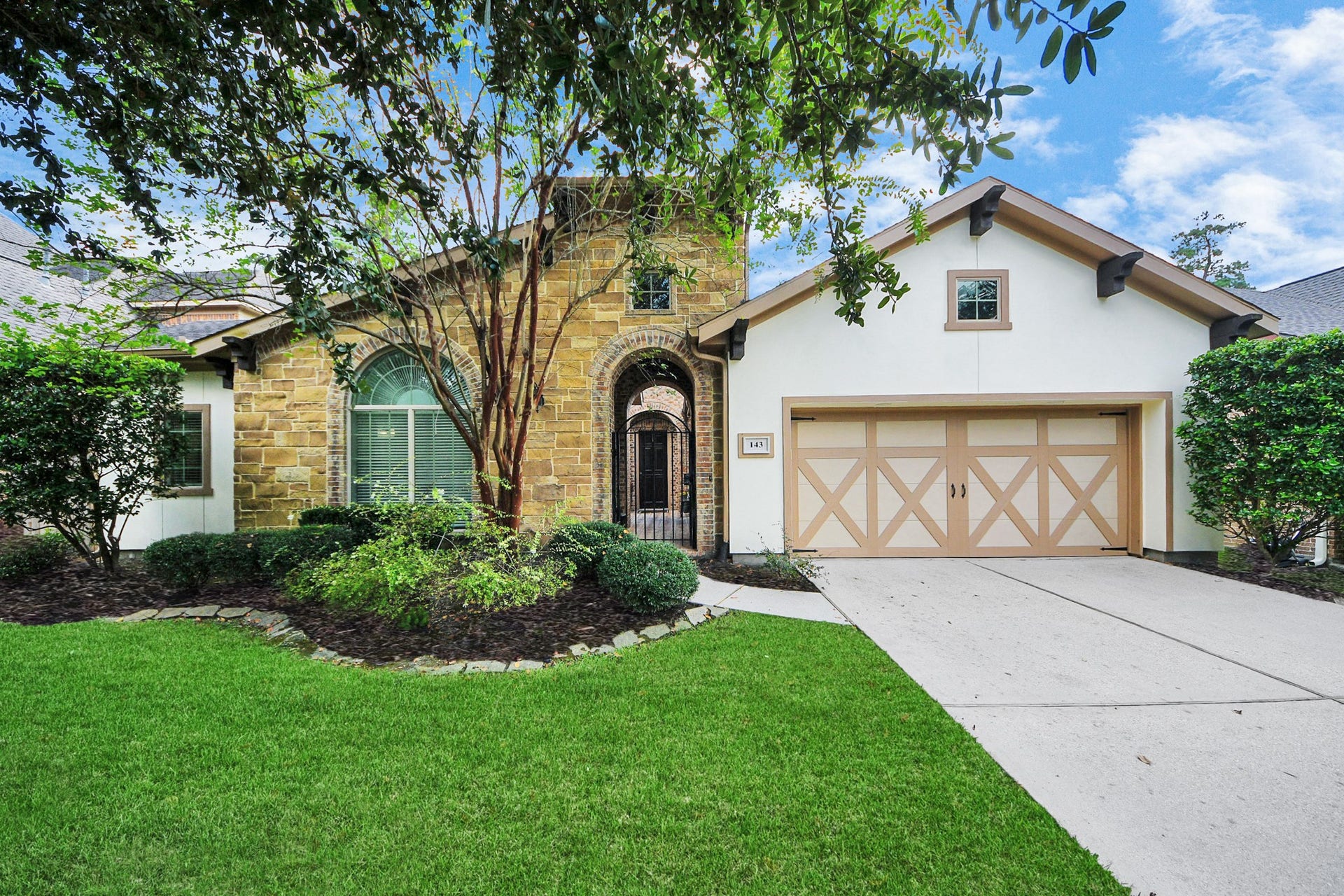 143 Pronghorn Place, Montgomery, TX 77316 Charming home with a beautiful stone facade, arched entryway, and a two-car garage. Lush landscaping and mature trees enhance its curb appeal.