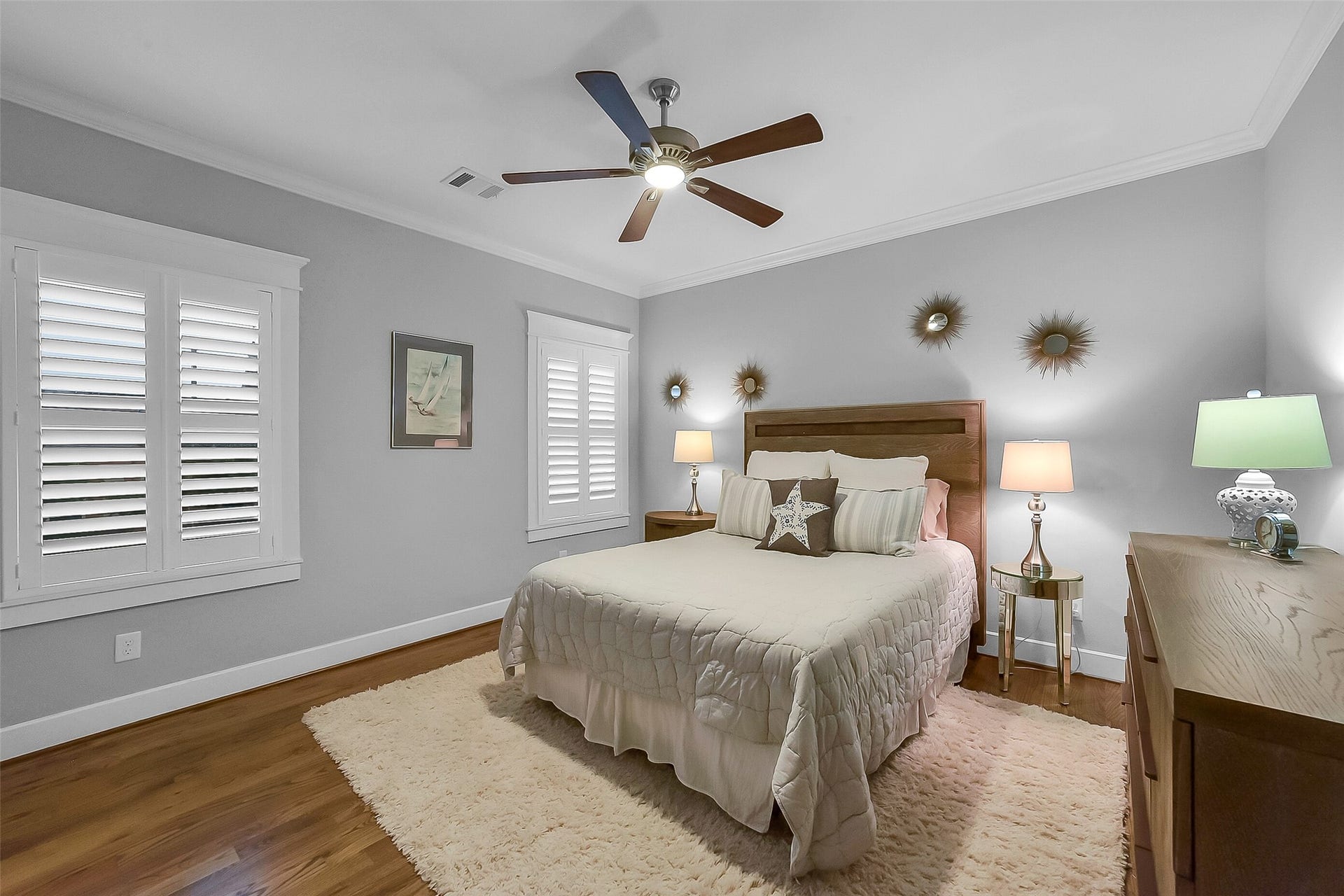 Comfortable secondary bedroom #1 located on the second floor, features hardwood flooring, crown molding, plantation shutters, ceiling fan, and direct access to the adjoining bathroom.