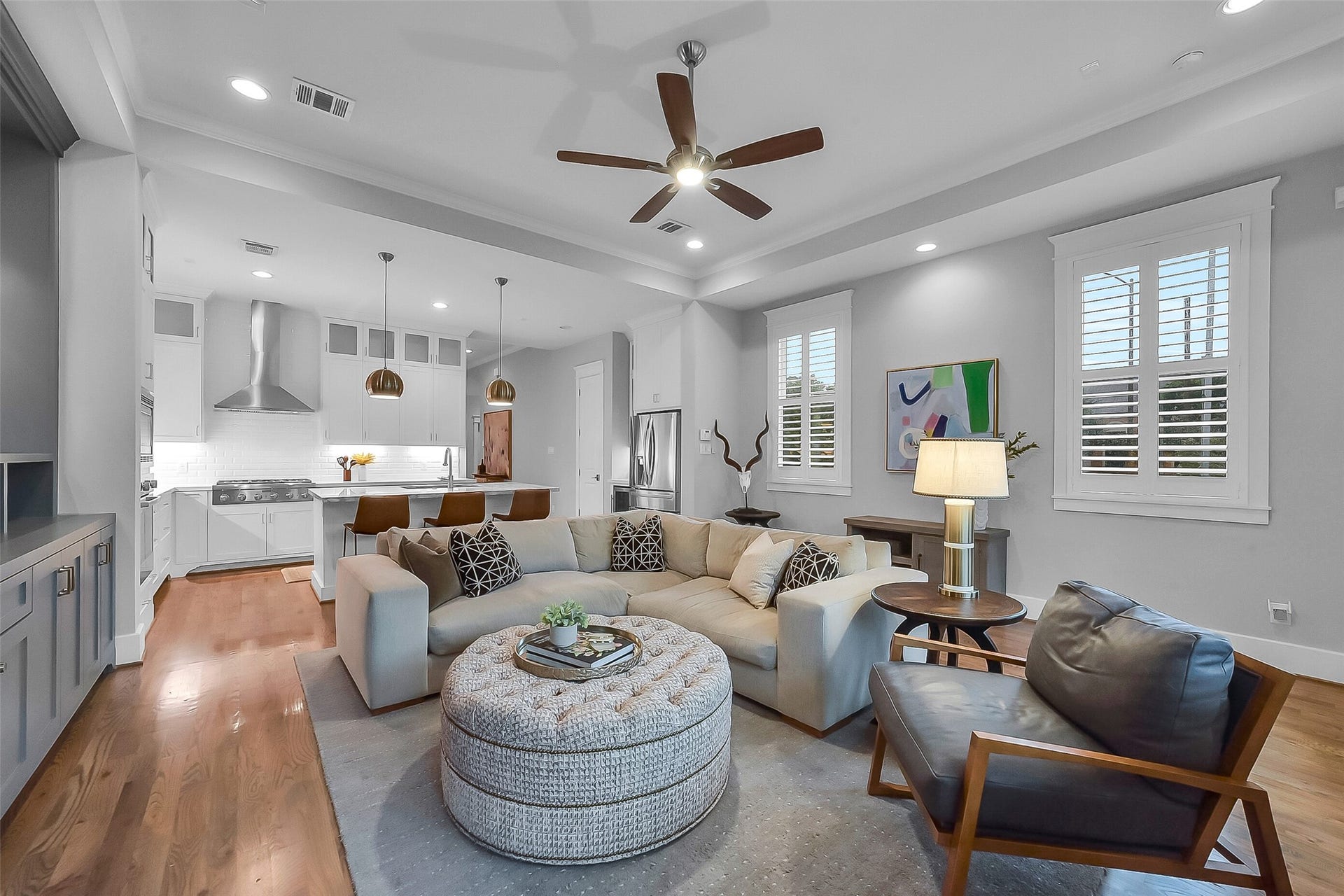 Spacious family room located at the rear of the home seamlessly opens to the kitchen, creating an ideal gathering space for everyday living. features a tray ceiling with crown molding and a ceiling fan.