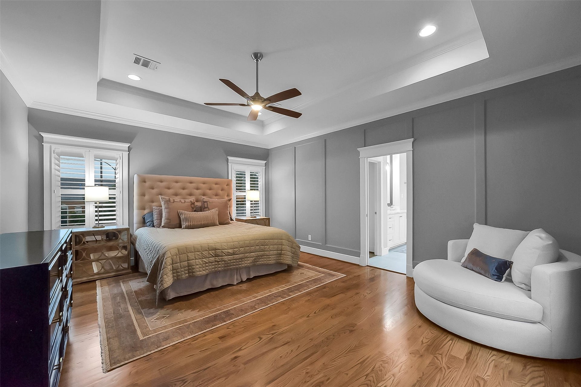 Second floor primary suite situated towards rear of the home, offering privacy. Spacious size offers flexibility for a variety of furniture arrangements. Features hardwood flooring, tray ceiling with crown molding, recessed lighting, ceiling fan, and three large windows with plantation shutters.
