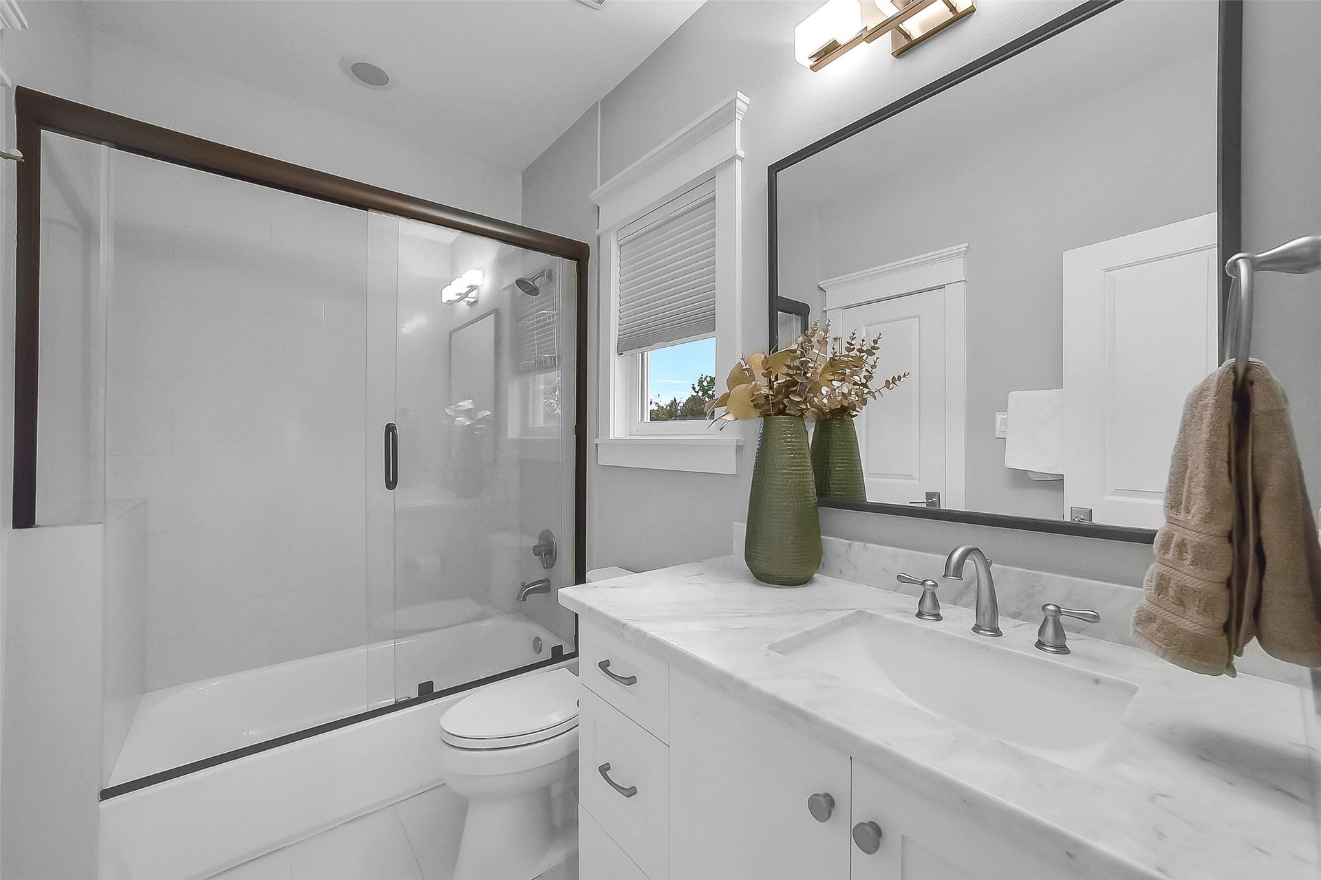 Well-appointed secondary bathroom upstairs for the 2 guest  bedrooms features a marble countertop vanity, polished nickel fixtures, tub/shower combination with sliding glass enclosure, tile flooring, and convenient dual access from both the hallway and secondary bedroom #1.