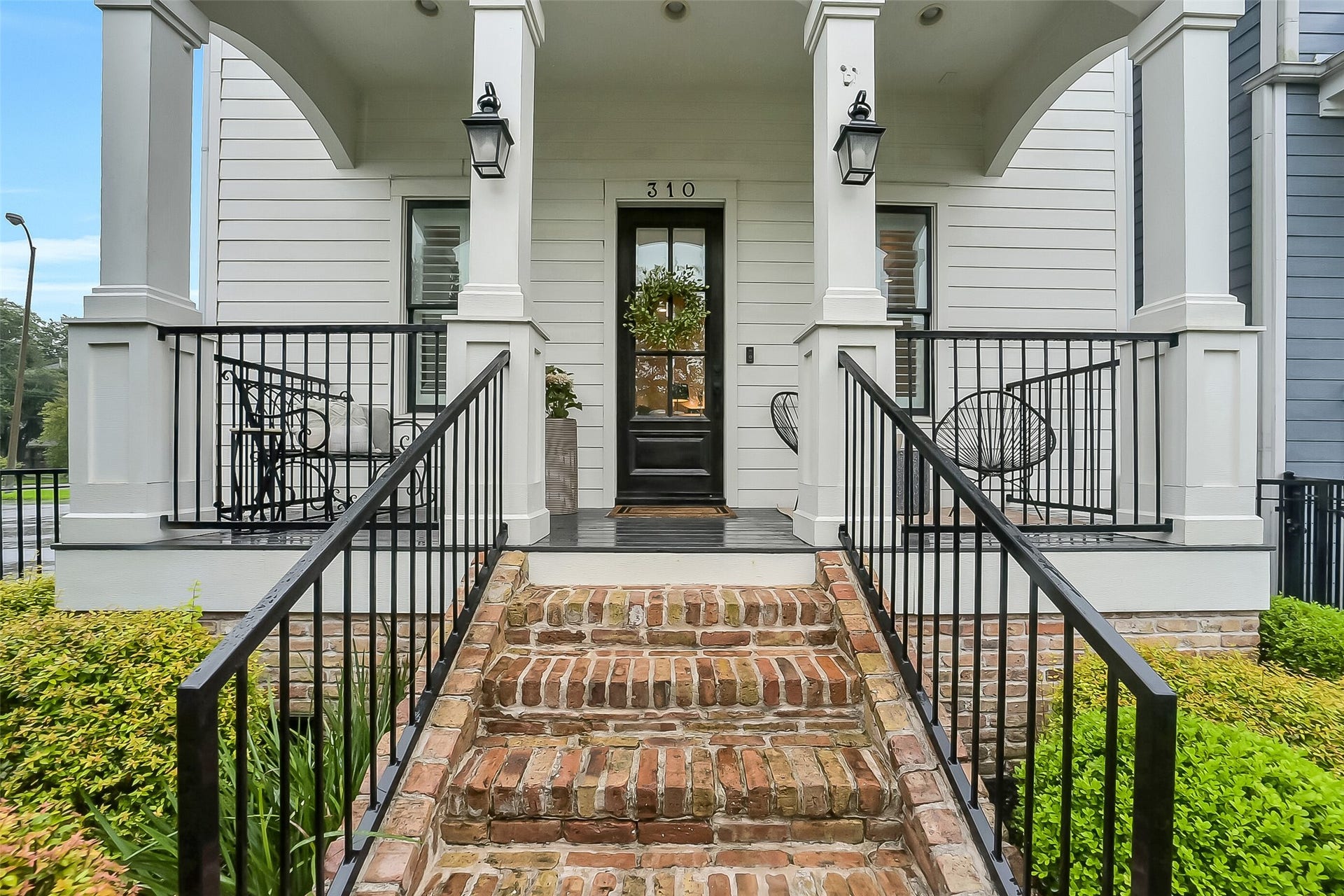 Bricked steps lead to the spacious covered front porch featuring wrought iron railing, lantern-style lighting, recessed lighting, and classic white columns. An inviting outdoor space ideal for enjoying one of Houston's most sought-after and walkable neighborhoods.. Enjoy easy access to the Heights Hike & Bike Trail, Halbert Park, neighborhood restaurants, local coffee shops, and convenient access to Downtown Houston.