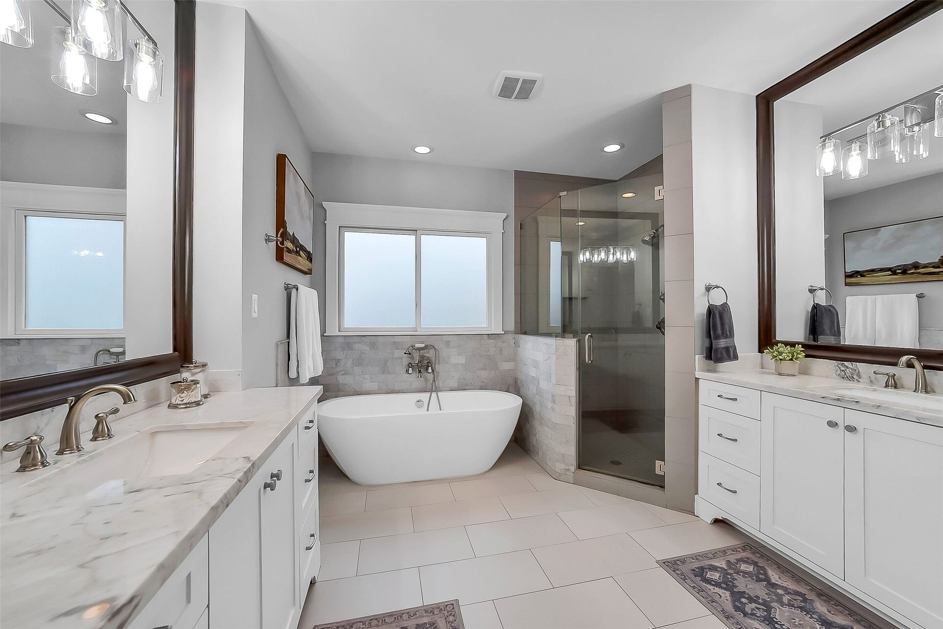 Beautiful spa-like primary bath. Elegant finishes create a timeless and sophisticated retreat. Relaxing soaking tub framed by marble subway tile surround and positioned beneath an oversized privacy window that fills the space with natural light. Oversized walk-in shower with frameless glass enclosure, handheld showerhead, wall-mounted showerhead, and built-in niche. Water closet. A perfect place to unwind at the end of the day.