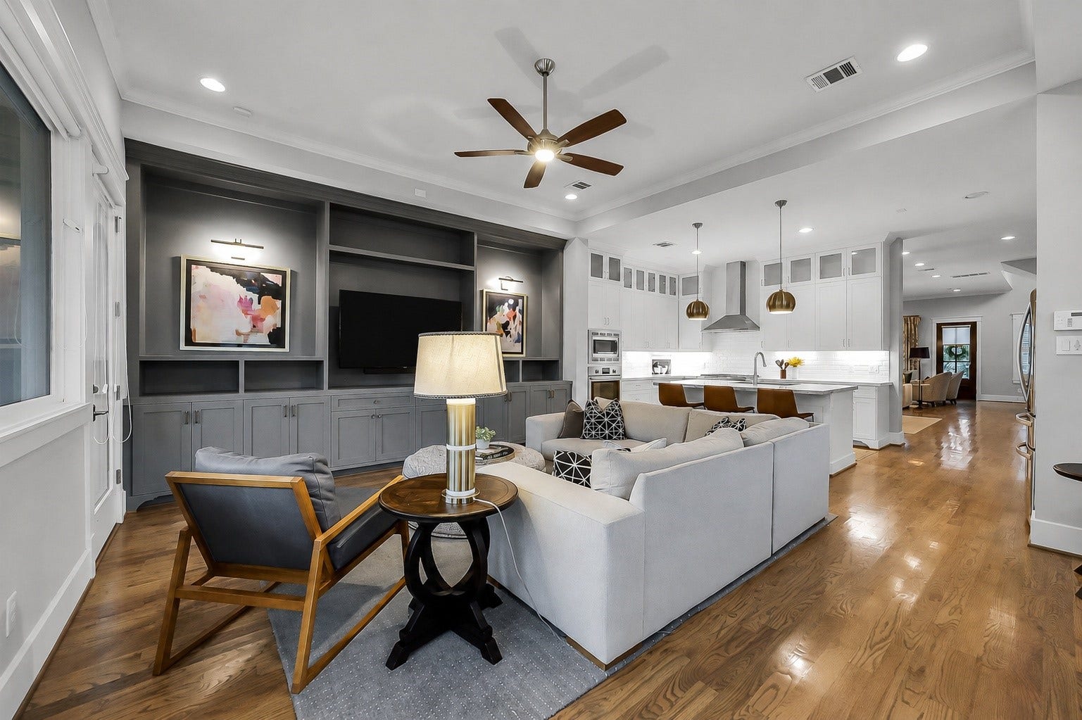 Another view of the family room highlighting the wall of built-ins the seller added w/ custom built-in cabinetry and shelving with art lighting provide both storage and an attractive focal point for art & a TV.