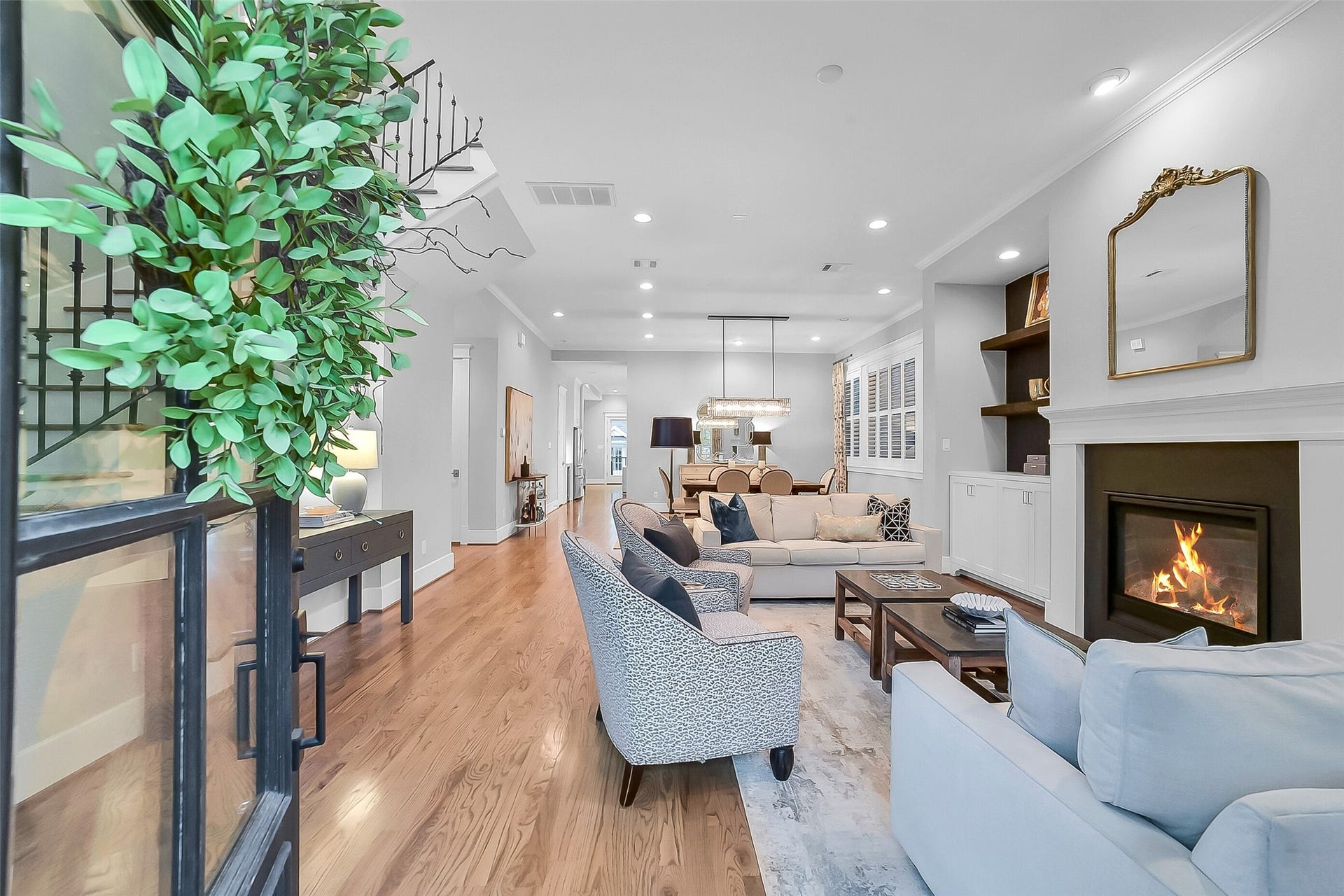 Welcoming foyer showcasing soaring first-floor ceilings, hardwood flooring, crown molding, and an open-concept layout. Upon entering, you will notice the beautiful sightlines connect the formal living and dining spaces while the elegant staircase with decorative iron railing on the left creates a striking architectural focal point.