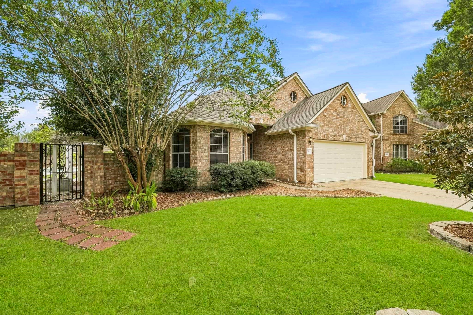 2611 Oxhill Court, Pearland, TX 77584 The home boasts a two-car garage, and a gated side entrance with a brick pathway.