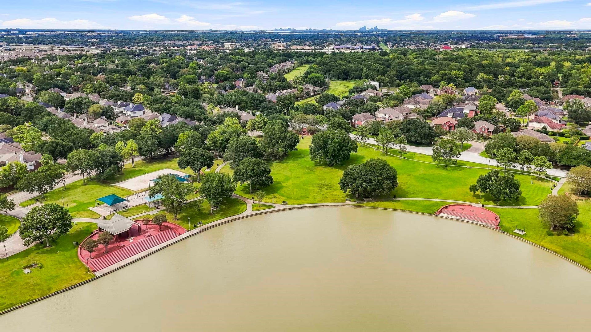 2611 Oxhill Court, Pearland, TX 77584 This beautiful aerial view showcases the communitys expansive lake surrounded by lush green space, mature trees, walking paths, and inviting recreational areas. The waterfront setting features open park space and gathering areas, creating a peaceful neighborhood amenity for enjoying the outdoors, scenic views, and community activities.