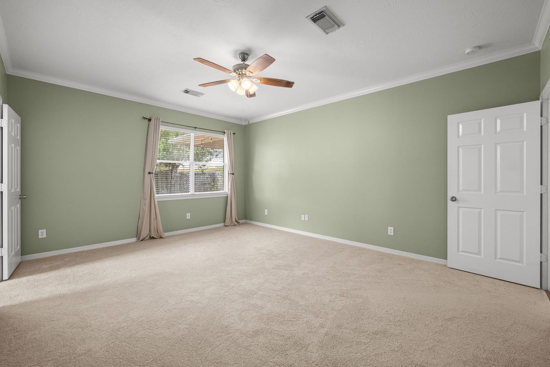 2006 Peonies Court, Pearland, TX 77581 Crown molding adds a refined finishing touch to the expansive primary suite, where new carpeting softens the space and a broad window draws in natural light with a pleasant view of the backyard.
