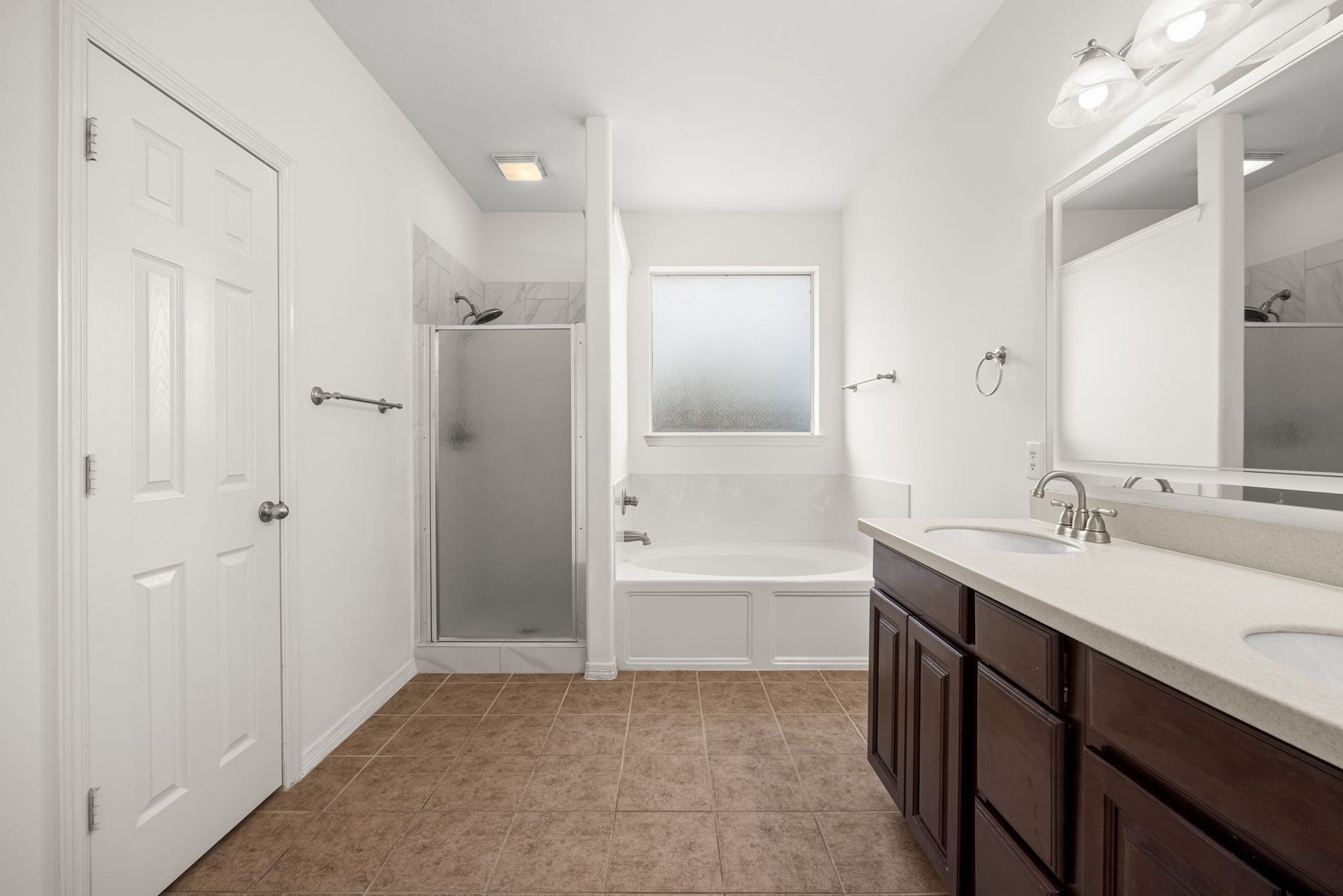 2006 Peonies Court, Pearland, TX 77581 The primary bath offers a generous dual-sink vanity, a deep soaking tub beneath frosted privacy glass, and a separate enclosed shower, providing distinct spaces for a quick morning routine or a longer evening soak.