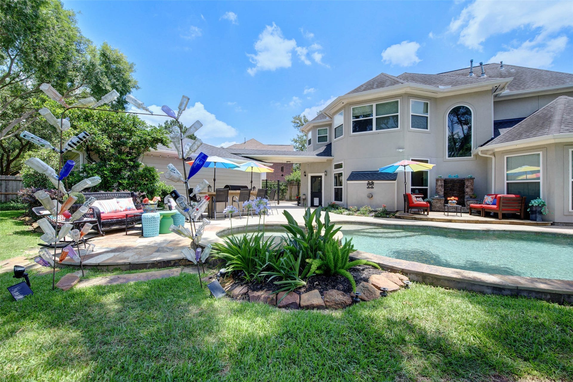 This backyard features a serene swimming pool with a waterfall, surrounded by lush landscaping and ample patio space for relaxation.