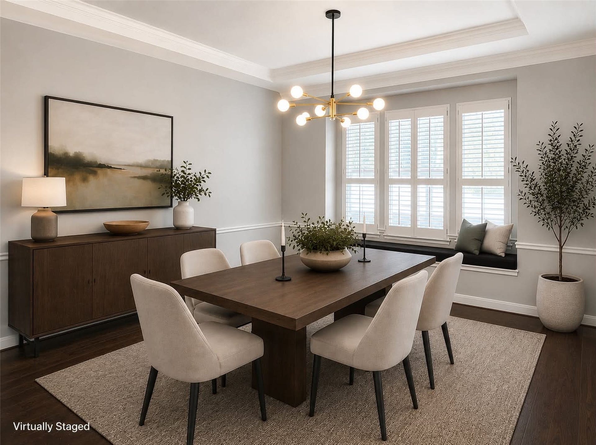 *virtually staged* photo showcases a stylish dining room with elegant light gray walls and white trim. It features a modern chandelier, large windows with shutters. The space is accented with dark wood flooring, offering a blend of sophistication and comfort. Custom crown molding that also continues throughout the house.
