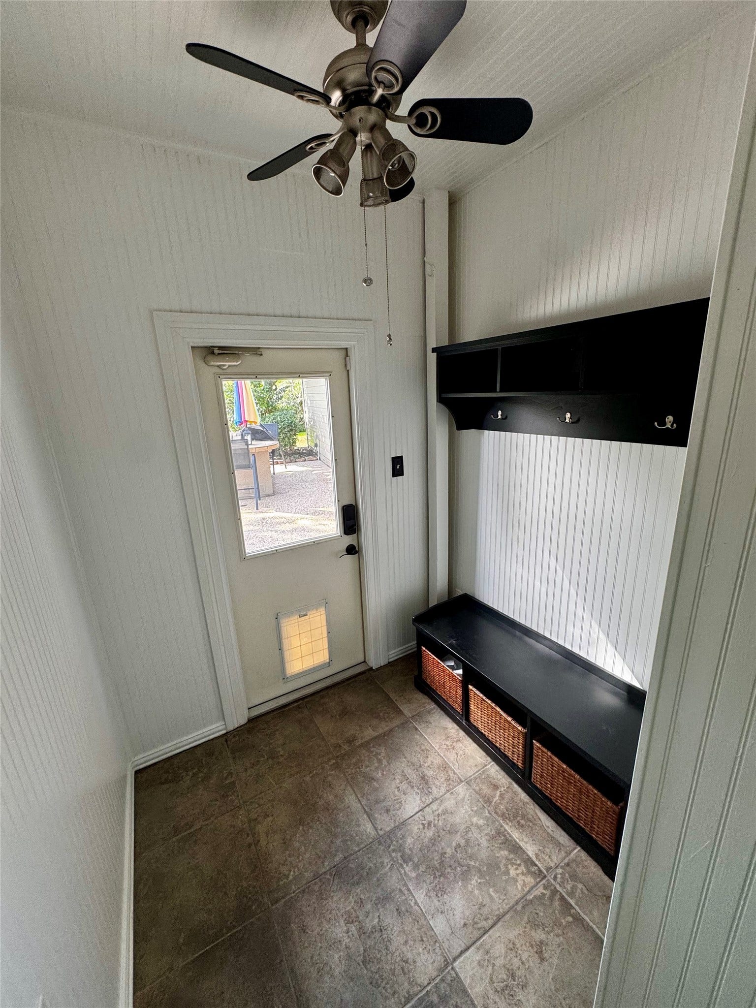 This entryway features a welcoming design with a bench and storage baskets for organization. Those stay with the house! Shelf with wall hooks offer space for hanging items. The exterior door provides easy outdoor access.