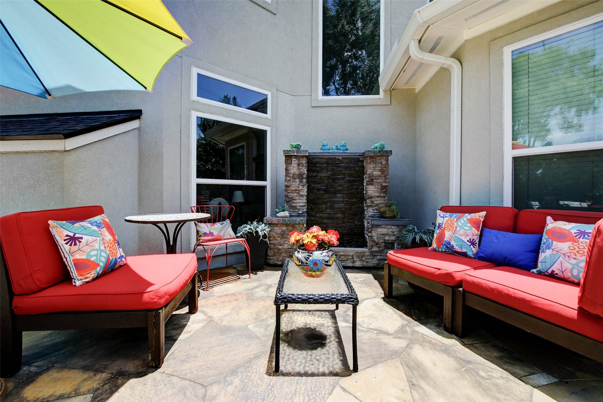 This inviting patio features a charming water feature. It's a cozy outdoor space perfect for relaxation and entertaining.
