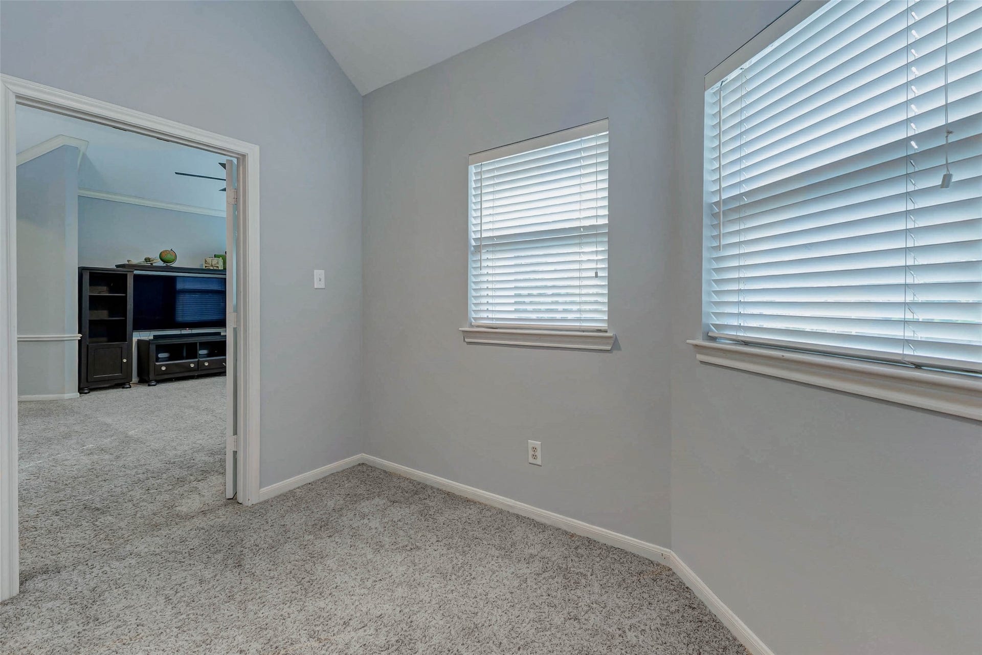 This photo shows 5th bedroom - great flex space room with three windows. It opens into the game room, suggesting a cozy and connected space. This could be study, craft room, nanny quarters, children's toy room, workout room. The options are endless!