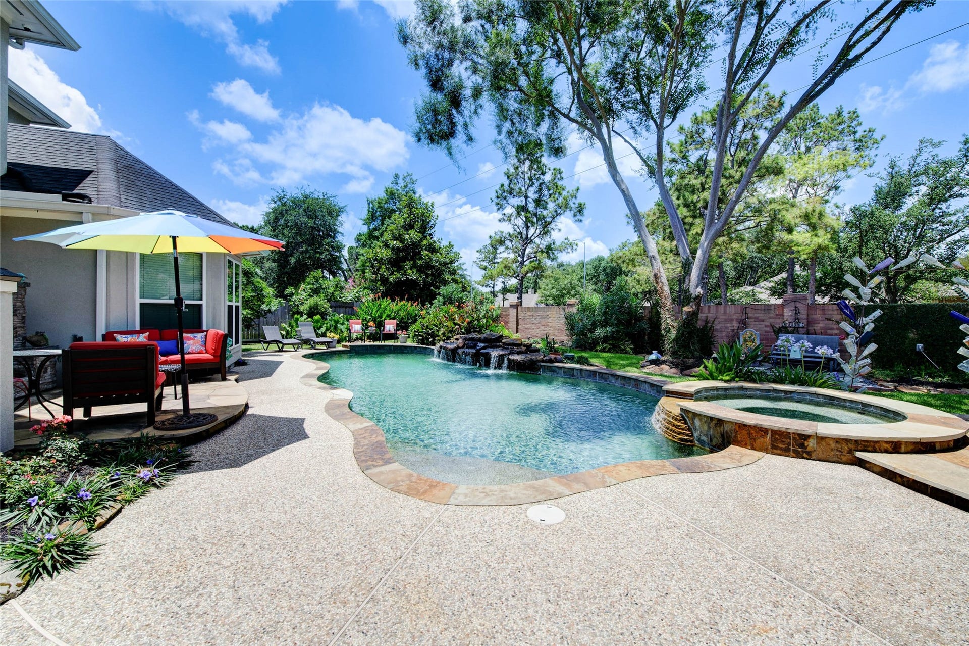 This backyard oasis features a sparkling pool with a waterfall, surrounded by lush greenery and vibrant flowers. Perfect for relaxation and entertaining. 4 surround sound speakers in backyard controlled from inside system.