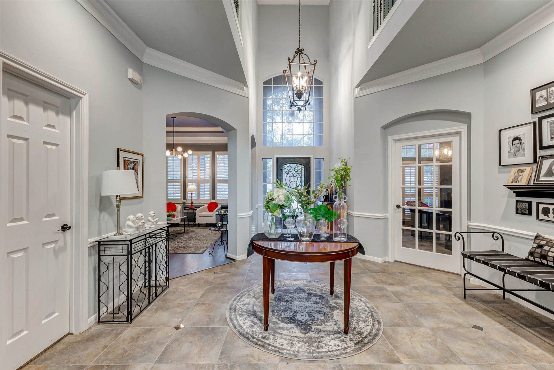This elegant foyer features a high ceiling, chandelier, and large windows, creating a bright and welcoming space. The vestibule offers tiled flooring, large entry offers access to the dining room, office, master bedroom, family room,  bath and the stairs.